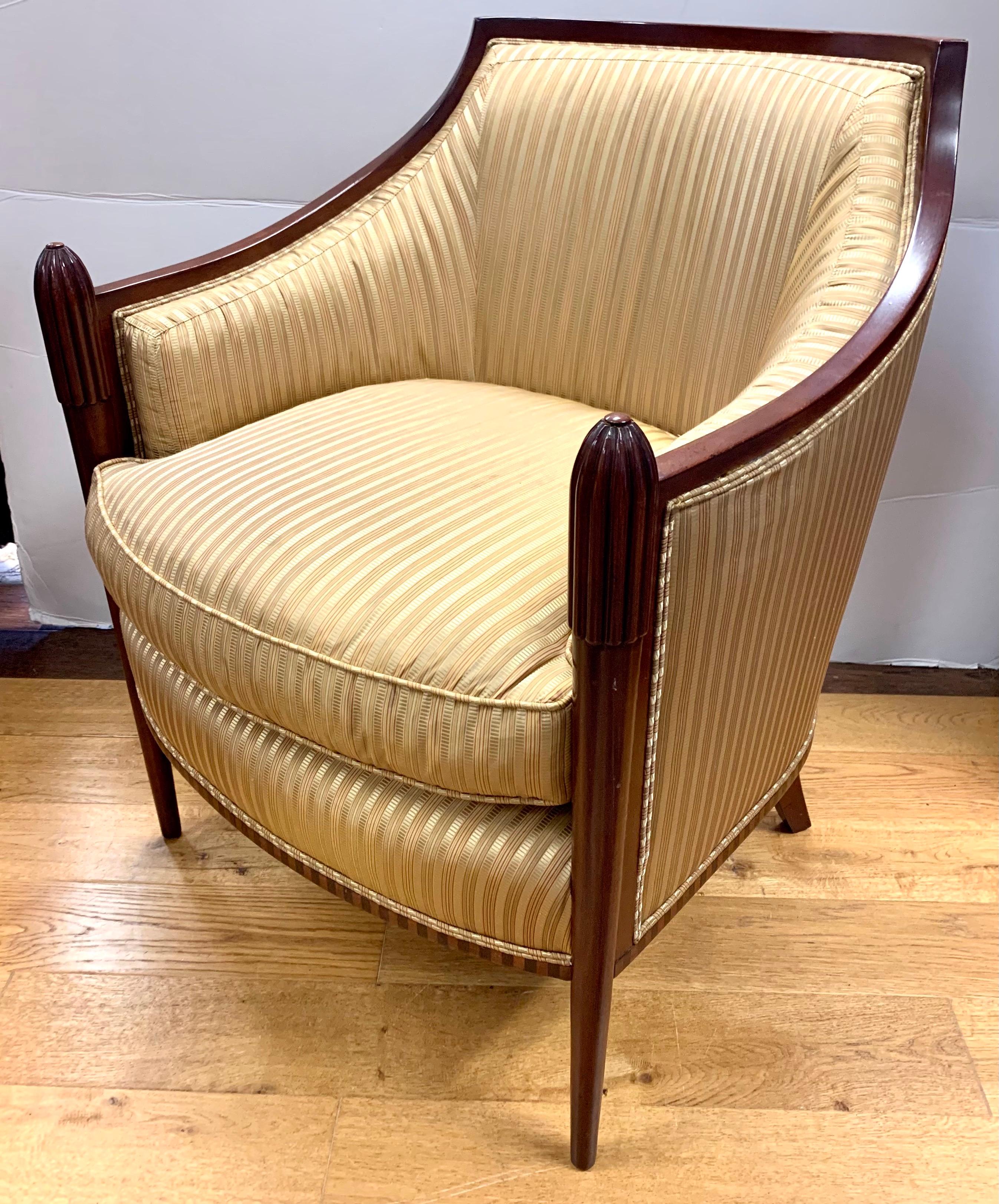 Elegant Baker mahogany barrel back armchair upholstered in a gold silk fabric features carved fluted arm to leg detail. Neutral color scheme makes it a timeless addition to any space.