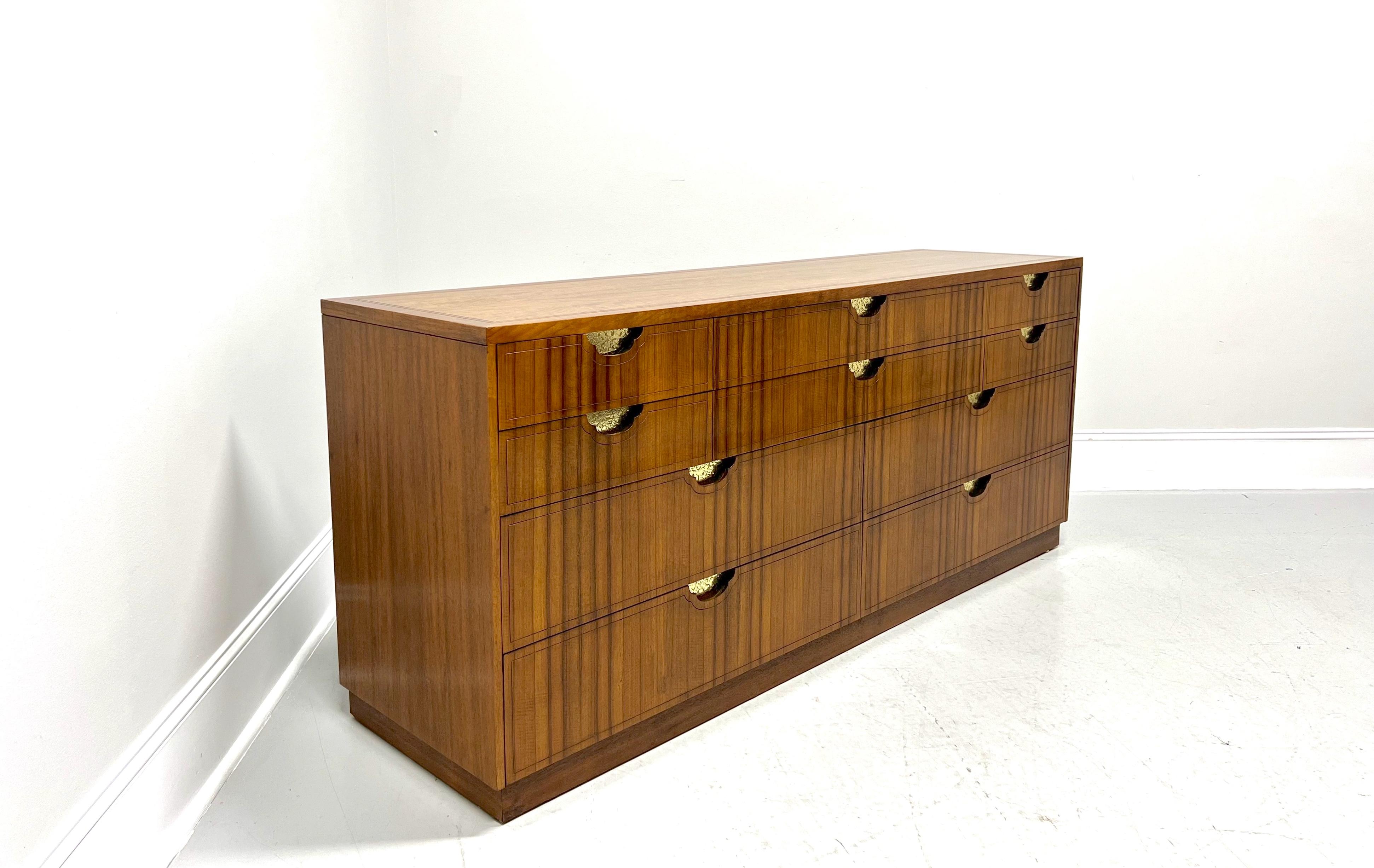 An Asian Inspired triple dresser by Baker Furniture. Walnut frame & top, rosewood drawer fronts, banded top with squared edge, decorative stamped brass accents, wood handles, and a solid base. Features ten various size drawers of dovetail