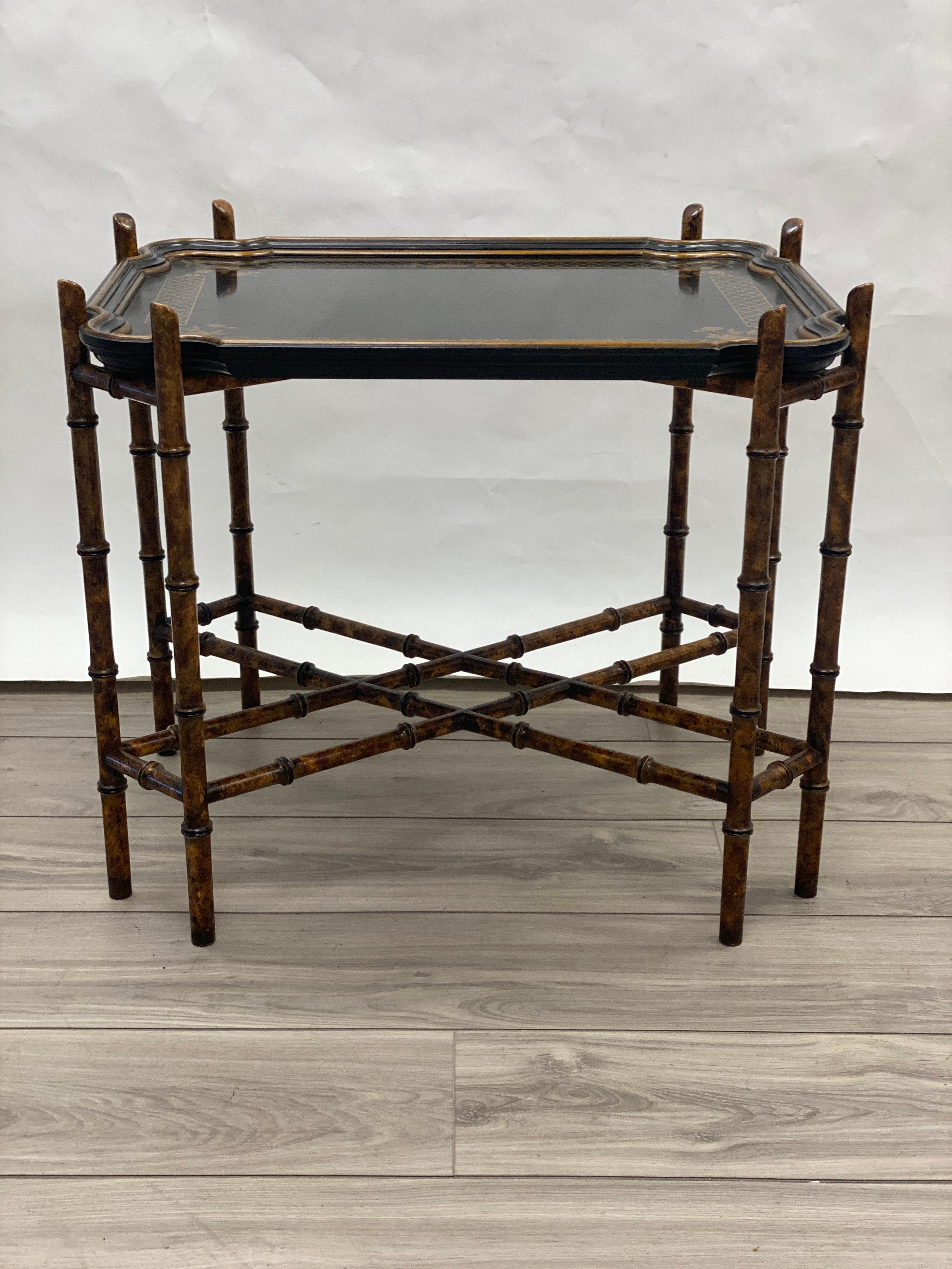 Ebonized and gilt wood removable tray resting upon a solid cross brace faux bamboo stand. Classic design of a very versatile table. 

 
