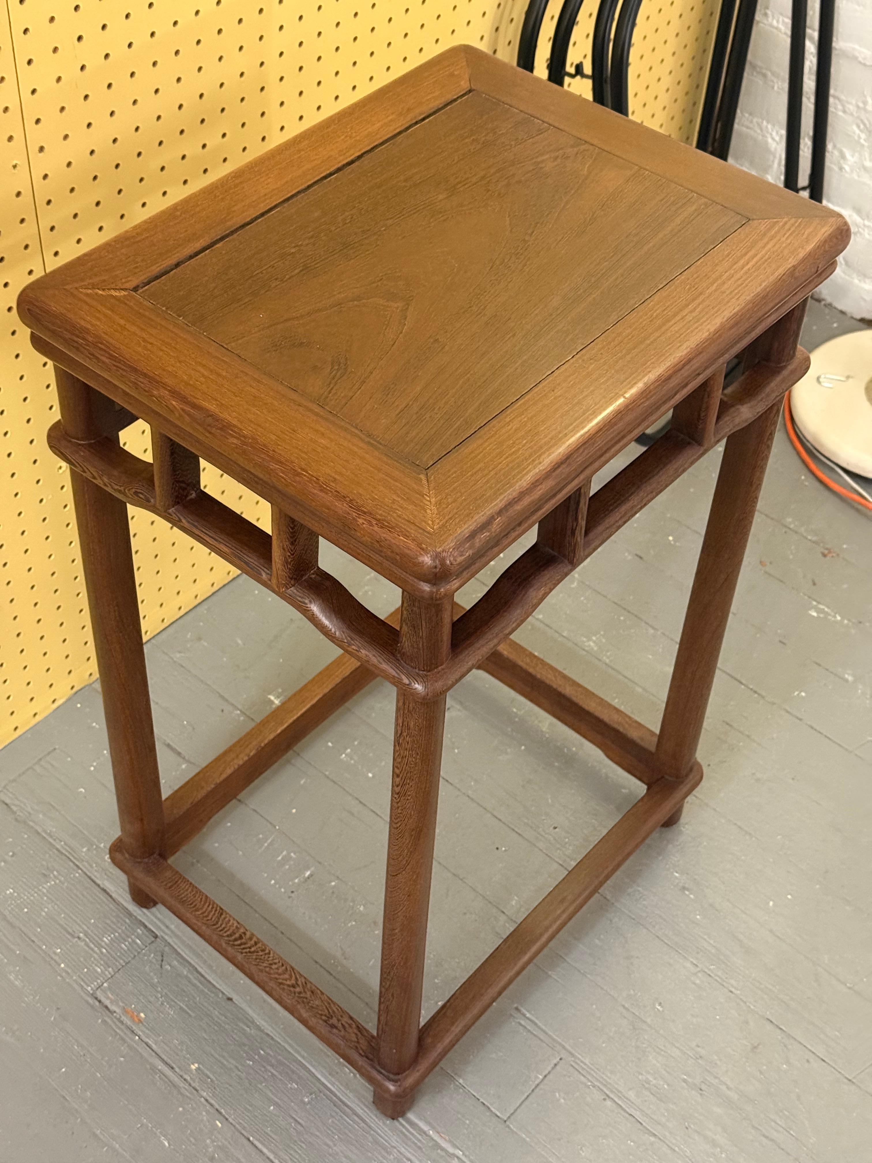 Un tavolo d'accento di metà secolo con piano rettangolare, profilo minimalista e sottili dettagli geometrici traforati sotto la superficie. 