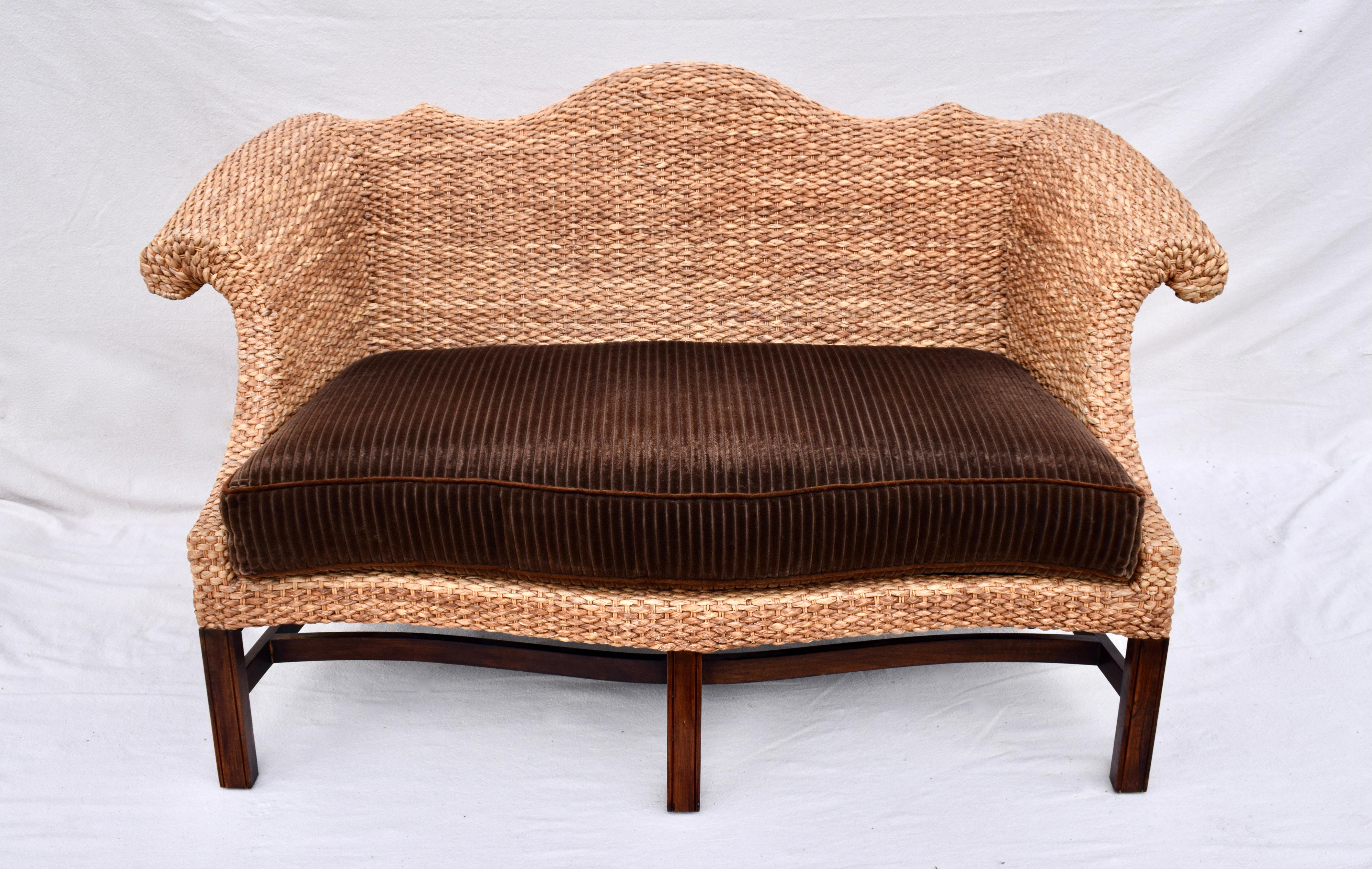 Rarely seen whimsical small scale George III style camel back sofa in the Chippendale manner by Baker Milling Road Furniture. Features most interesting materials in the tightly woven water hyacinth rattan and solid walnut frame, plush goose down