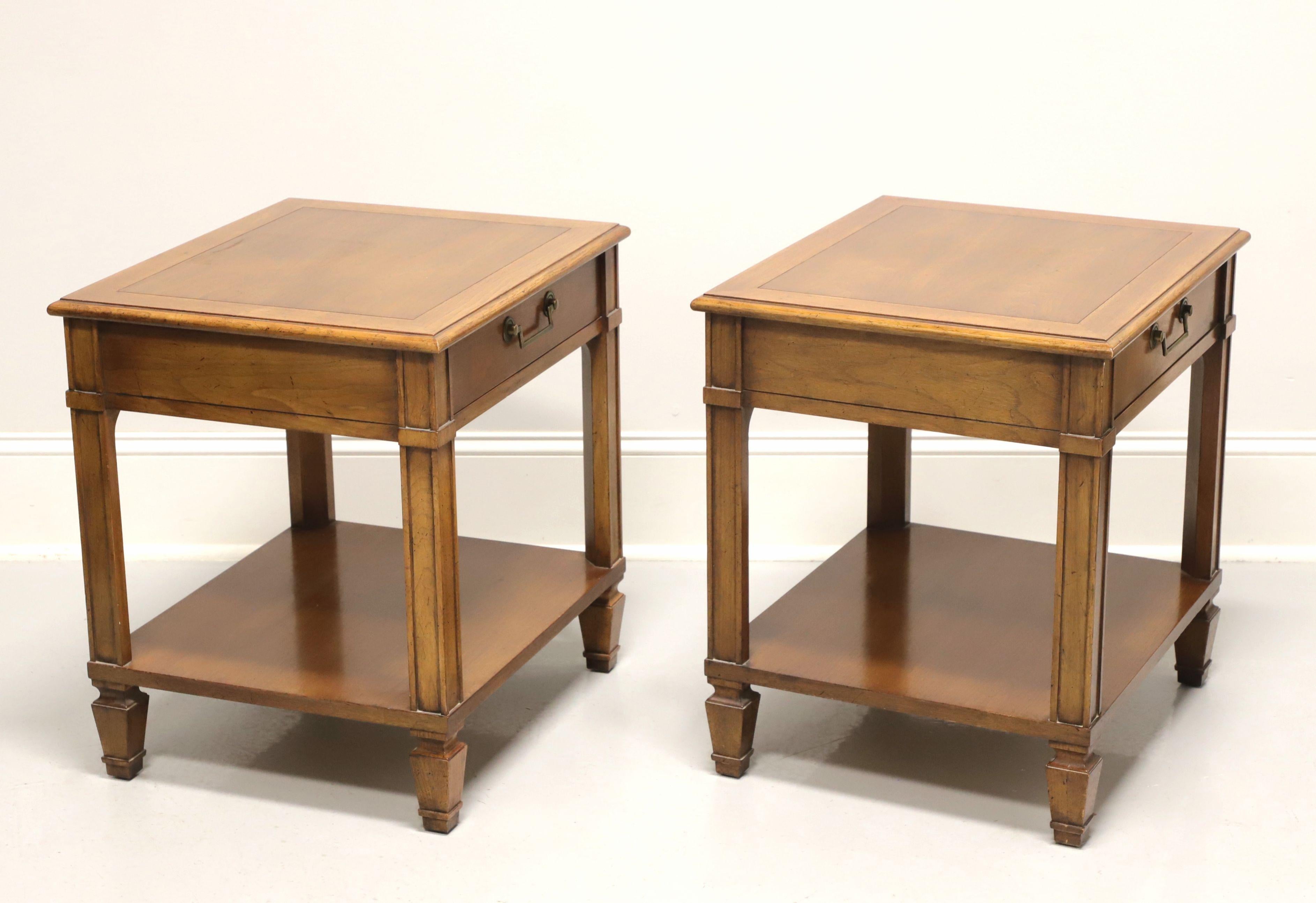 A pair of classic Mid Century style nightstands by Baker Furniture Company, for their Milling Road Division. Walnut with slightly distressed finish, banded top, brass hardware, column-like sides, undertier shelf and spade feet. Features one drawer