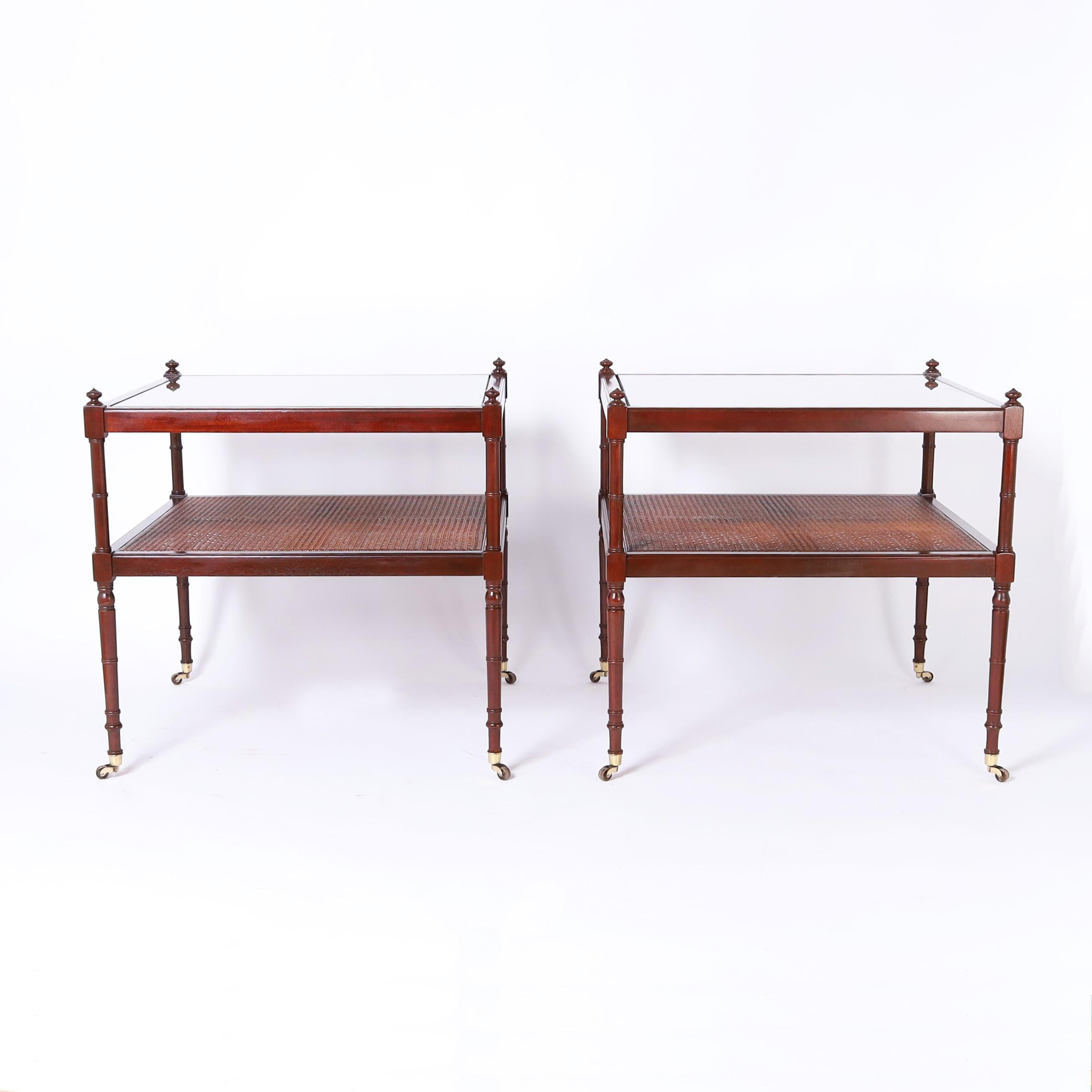 Large scale pair of mid century British colonial style stands with two caned tiers having turned supports with finials at the tops, classic legs and brass casters. Signed Baker on the bottoms.