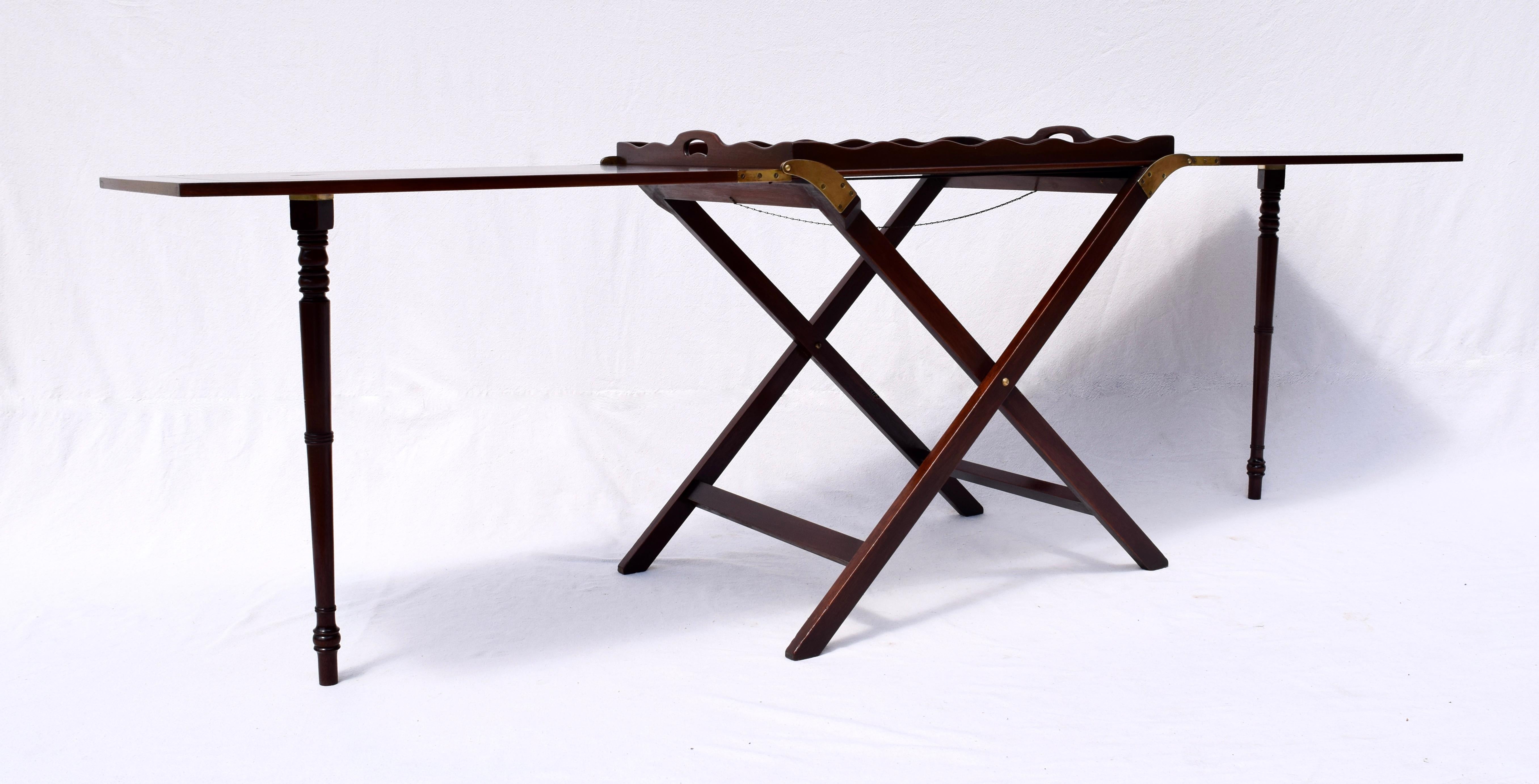 Butler tray table, with folding X-base, in most desirable mahogany finish by Baker Furniture. Two flush panel butterfly leaves unfold from the center on heavy brass hinges to create a 92