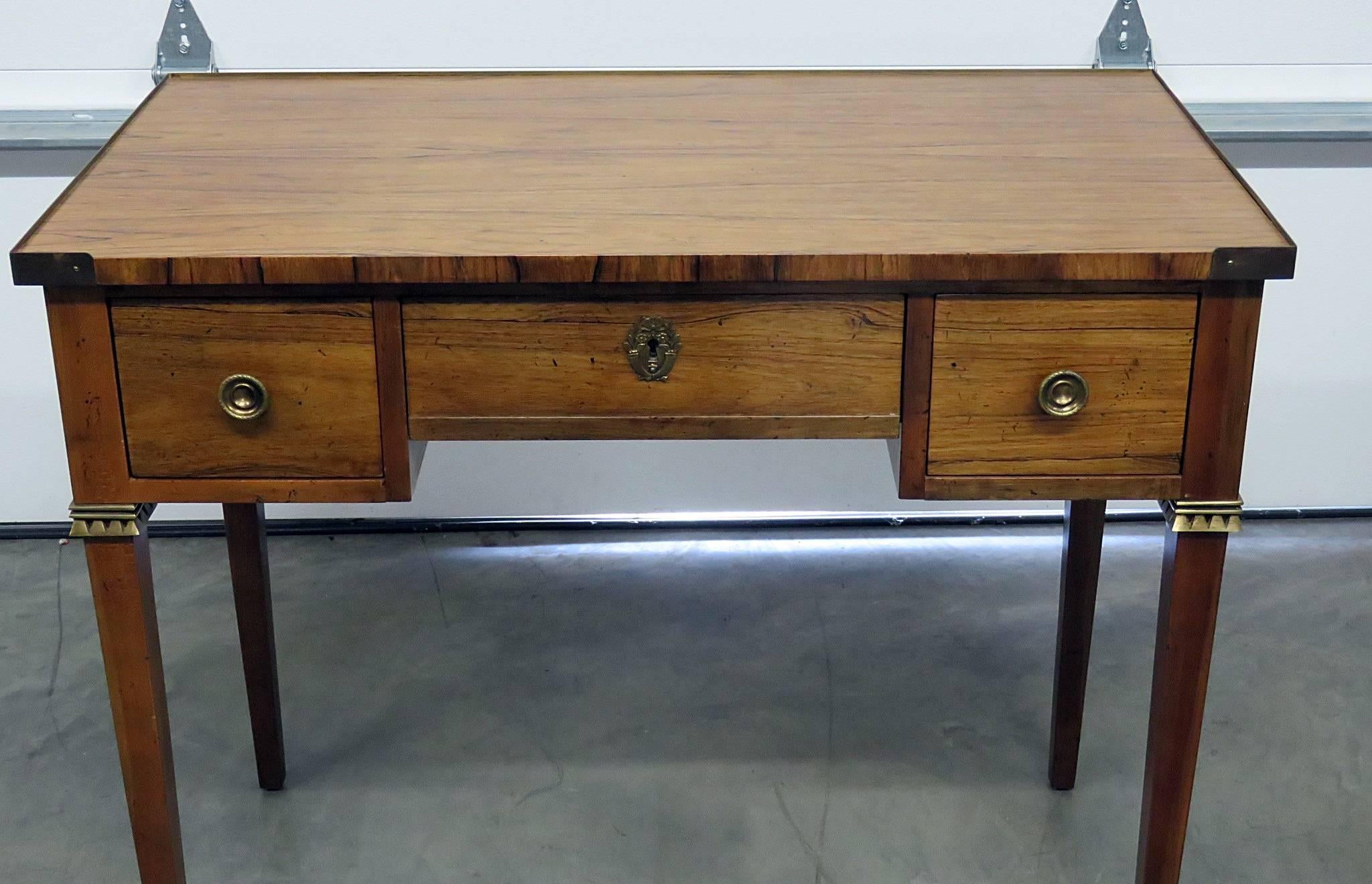 Regency style rosewood desk by Baker. Three drawers with brass accents and trim.