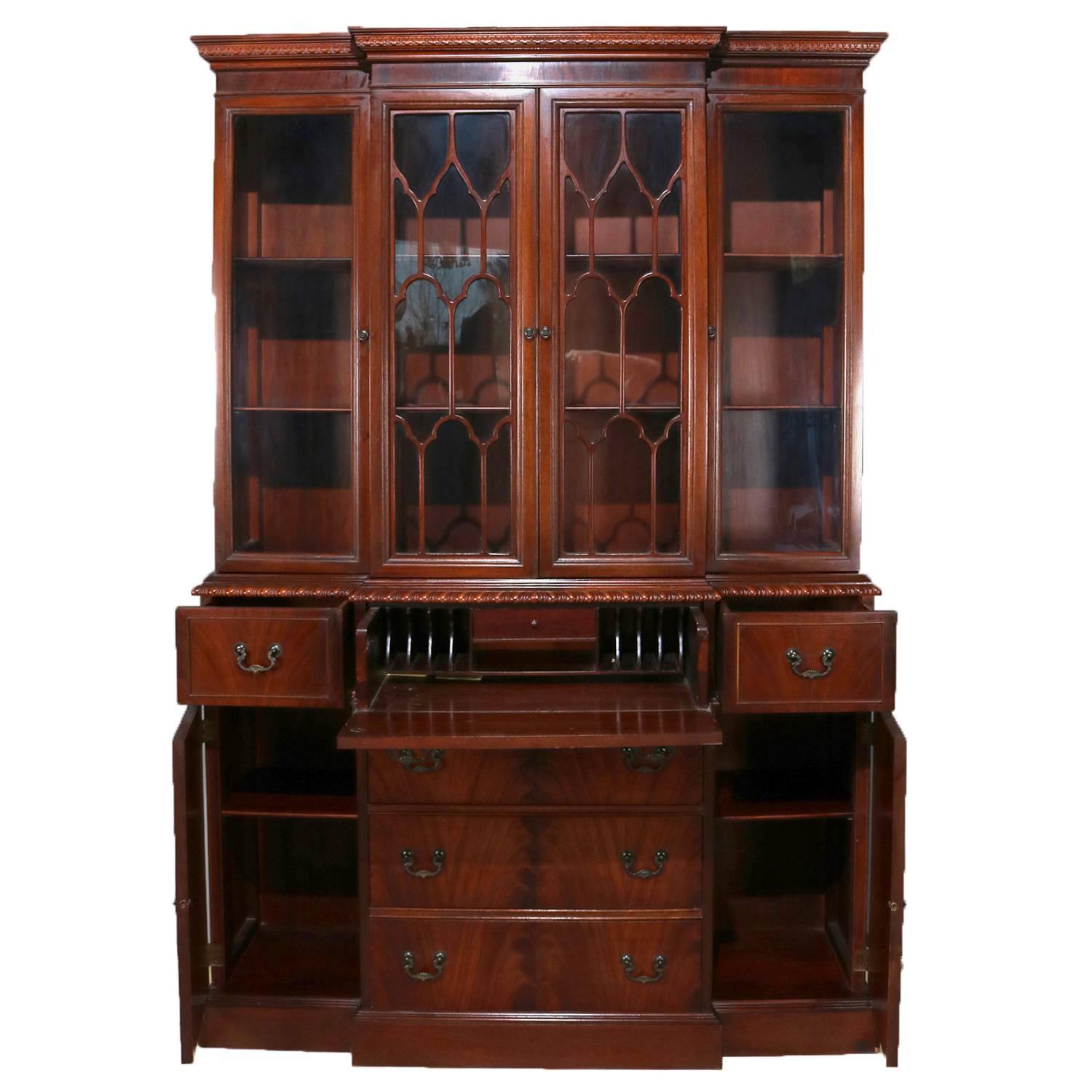 Baker School Colonial flame mahogany breakfront features central upper cabinet with double deeply striated glass doors and flanking recessed side cabinets each with glass door, central drop front secretary opens to writing desk and pigeon holes and