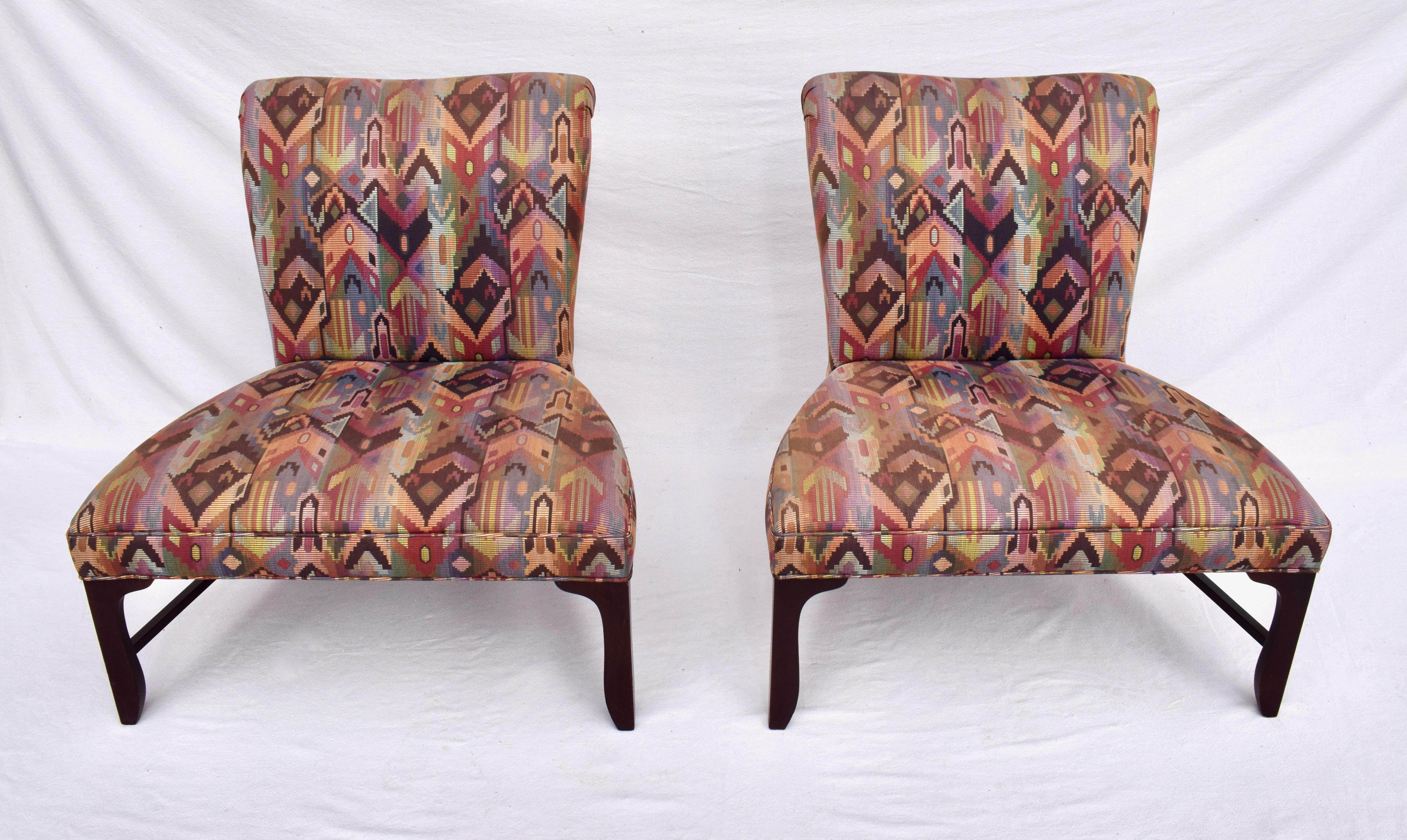 A pair of Mid-Century Modern oversized slipper chairs by Baker Furniture. The chairs feature mahogany legs & stretchers with subtle elegant curves and original Southwestern tapestry style upholstery. In nicely maintained all original condition, the