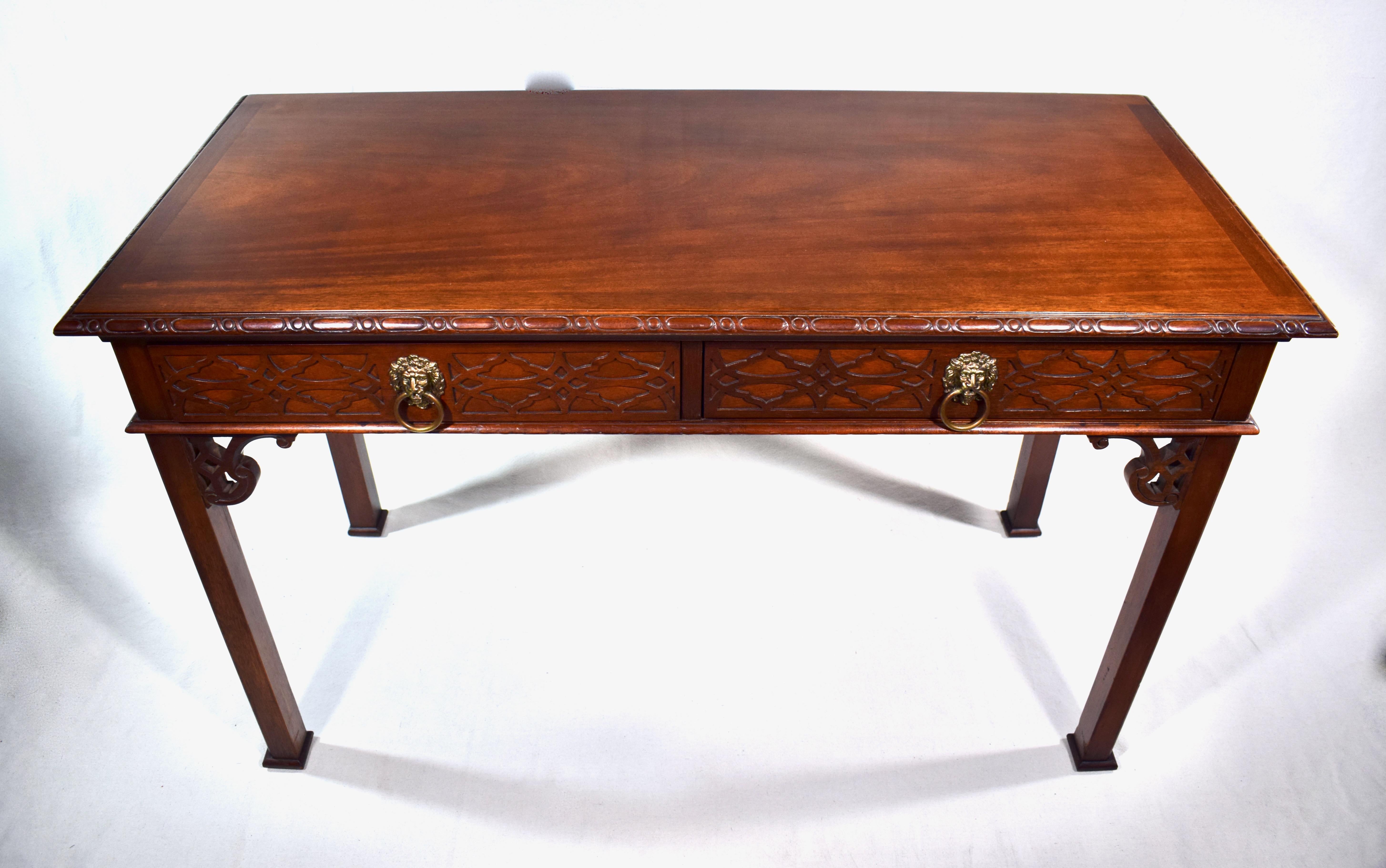 Midcentury Chinese Chippendale style mahogany writing desk or console table with two drawers, solid brass lion's head pulls and a custom glass top. This is a lovely small scale aesthetically pleasing table that can work well in a variety of