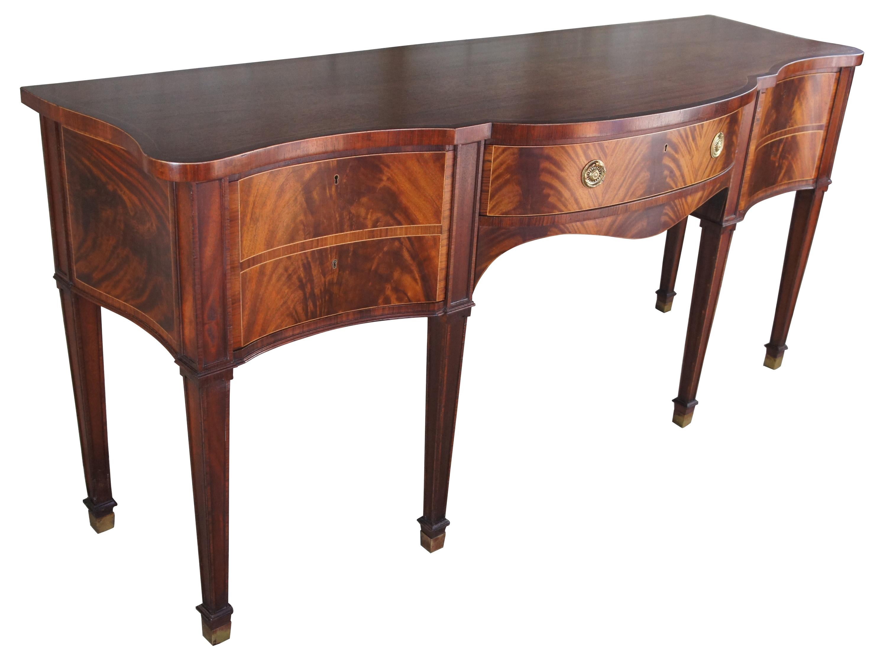 Baker Stately Homes flamed mahogany sideboard serpentine buffet Sheraton style

Shaped banded mahogany top with string inlay, single central drawer with single deep drawer either side, tapered legs. Center drawer with paper label ''Stately Homes