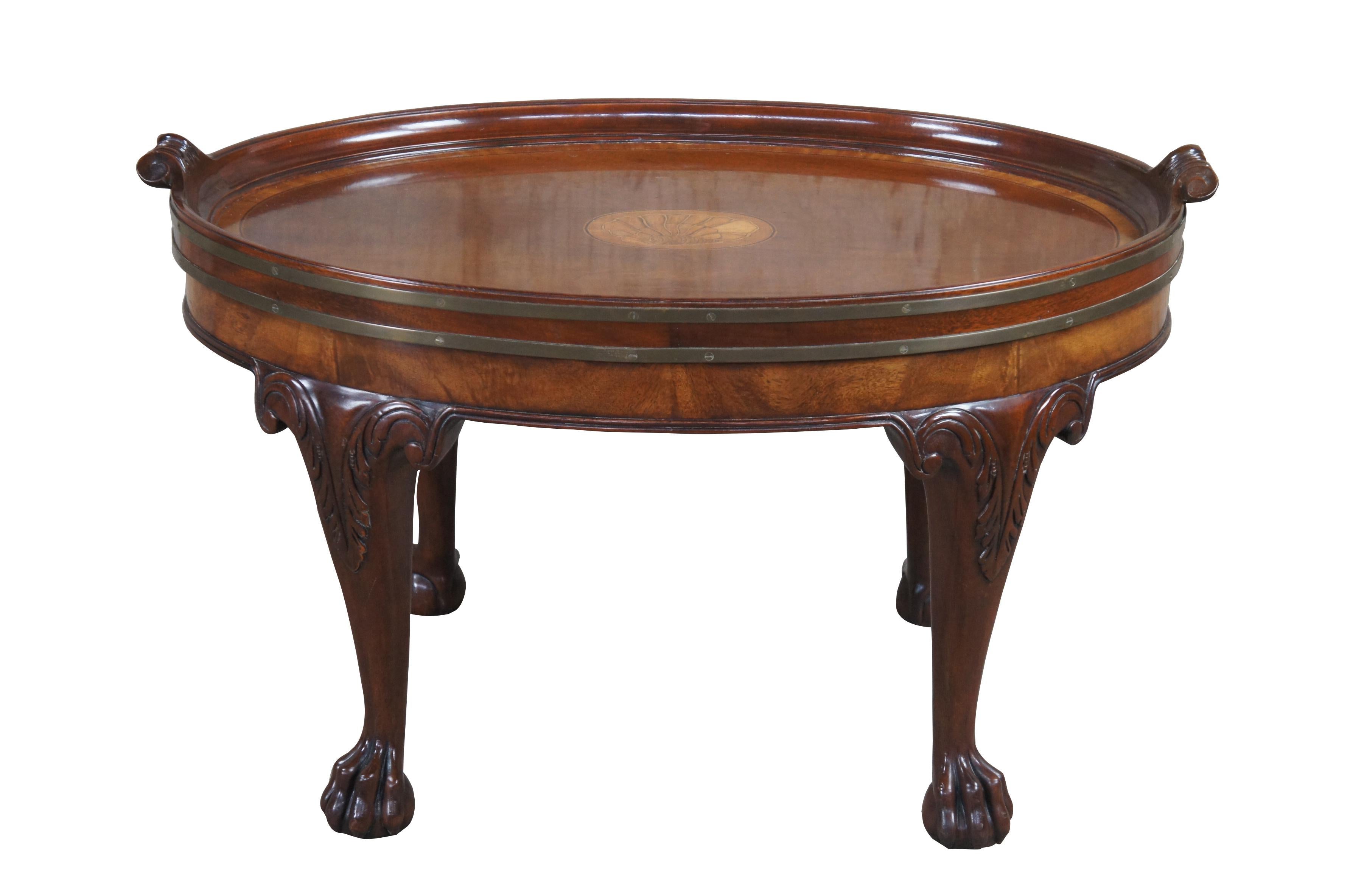 Vintage Baker Furniture Stately Homes Collection coffee table.  Drawing inspiration from English Georgian and Chippendale styling.  Made from mahogany and satinwood with an oval form and tray style inset top.  Features marquetry inlay with sea shell