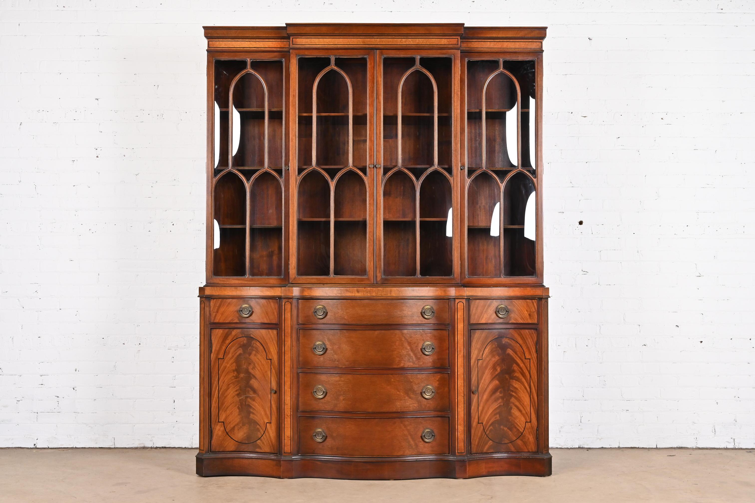 A gorgeous Georgian or Chippendale style breakfront bookcase or dining cabinet with secretary desk

In the manner of Baker Furniture

By Fancher

USA, Mid-20th Century

Beautiful flame mahogany, with ebony inlay, mullioned bubble glass front