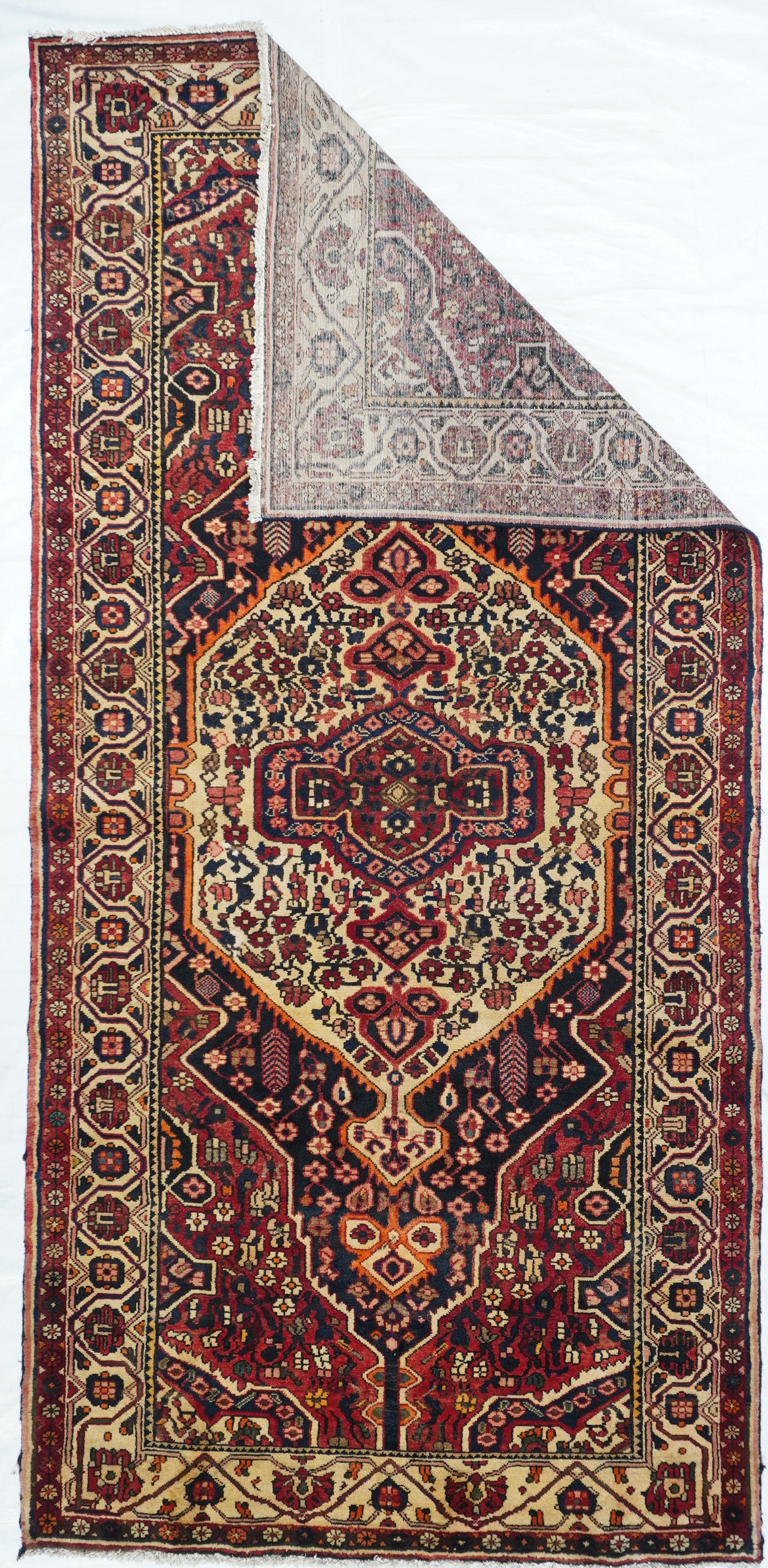 This kelegi (long rug) format Chahar Mahal rustic weaving shows a full-width, doubly pendanted ecru floral medallion, enclosing a conforming doubly pendanted sub-medallion, all on the navy field. Red extended corners and pendanted navy sub-corners.