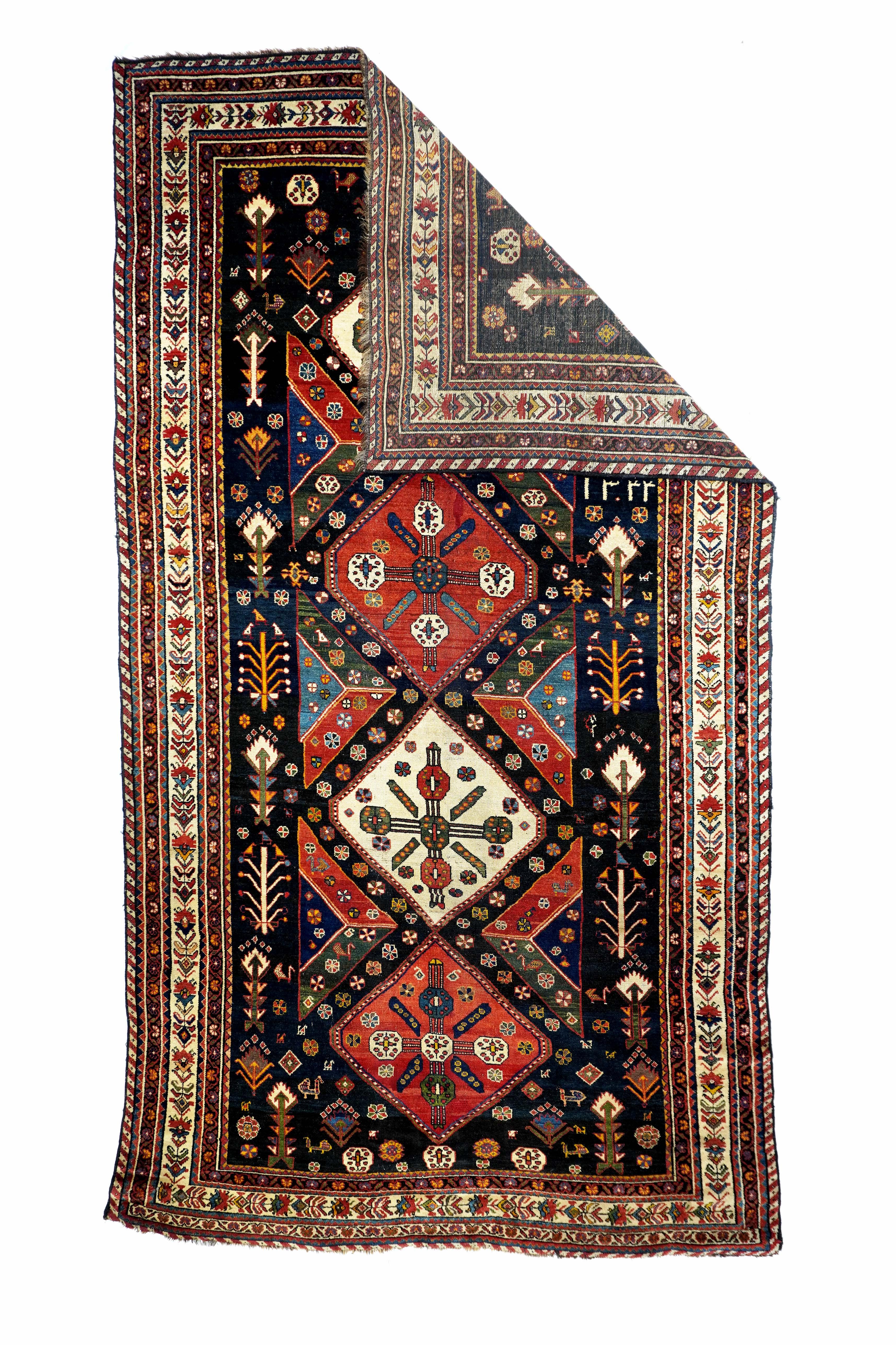 This rare nomadic long rug shows a navy ground with four nearly diamond-shaped, micro-stepped medallions in red and ecru, with radiating five rosette inner ornaments. Trapezoidal and triangular floating side fillers in green, red and navy. Side