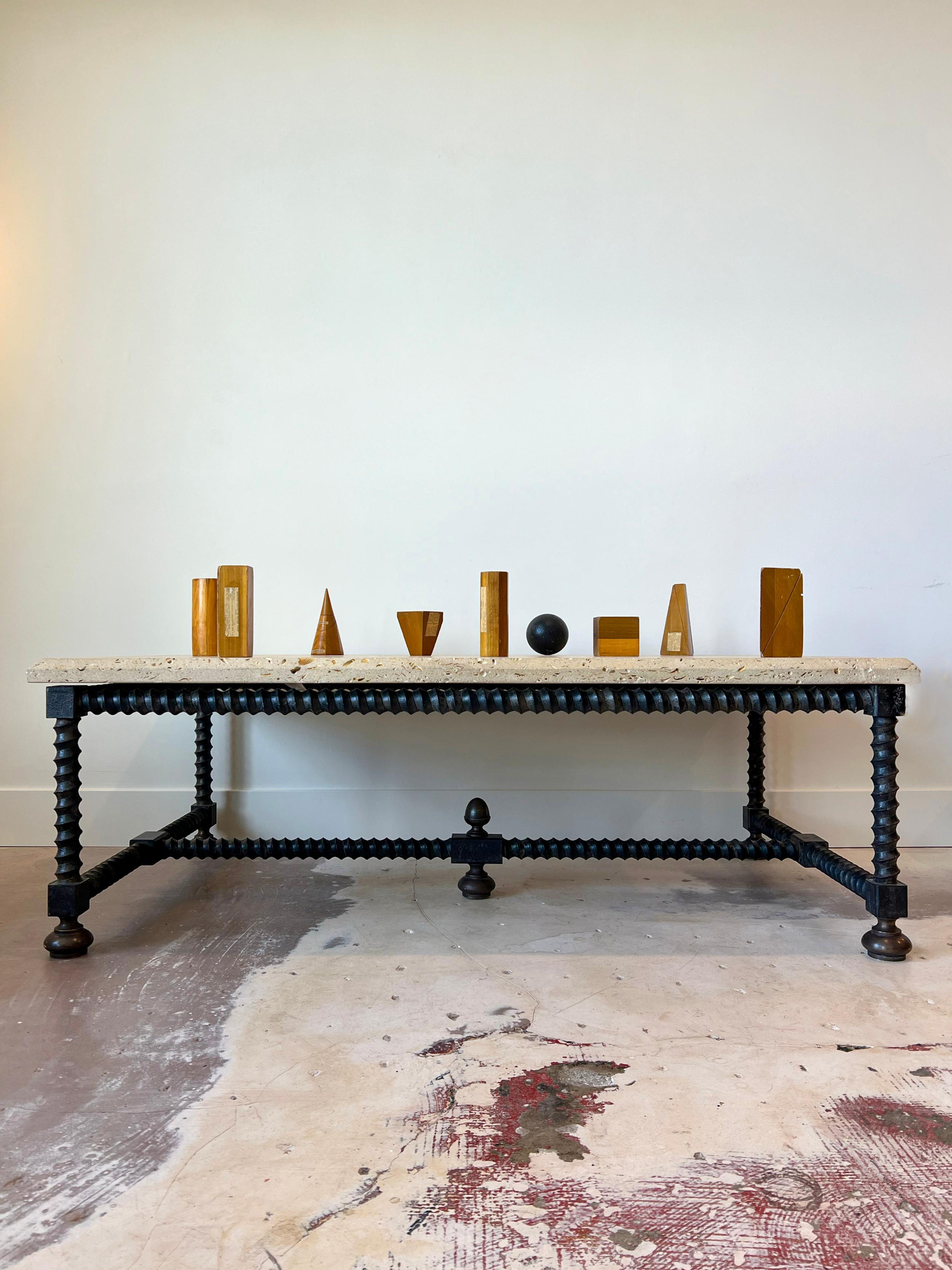 Baldacchino coffee table with natural solid shellstone top and heavy iron base. The top features beautiful voids and shell fossils, framed by a chamfered edge. The base is made of iron mimicking turned wood. 4 adjustable/removable feet. 2 available