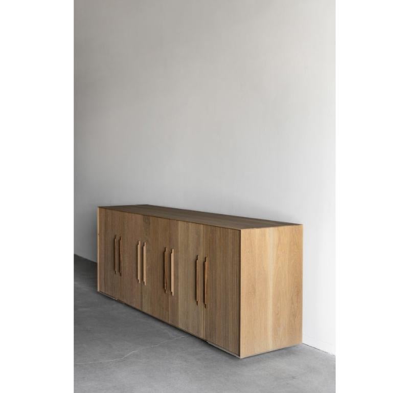 La credenza Baldwin è realizzata a mano a Los Angeles, in California. L'involucro in rovere ha un profilo sottile che delimita splendidamente le porte. Tutte e cinque le ante presentano un frontale verticale in quercia a scanalature piatte, rifinito