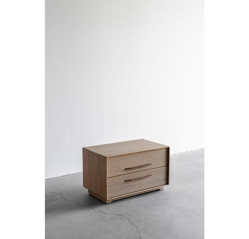 The Baldwin Nightstand is handmade locally in Los Angeles, California. The oak casing has a thin profile that borders the drawers beautifully. The two storage drawers showcase a horizontal flat fluted oak face, finished with a natural toned durable