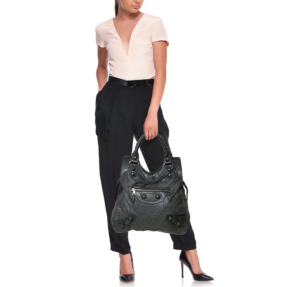 This Balenciaga bag is perfect for everyday use. Crafted from leather in a gorgeous shade of grey, the bag has a feminine silhouette with two top handles, a front zip pocket, and a zip closure that opens to a fabric-lined interior. This piece is