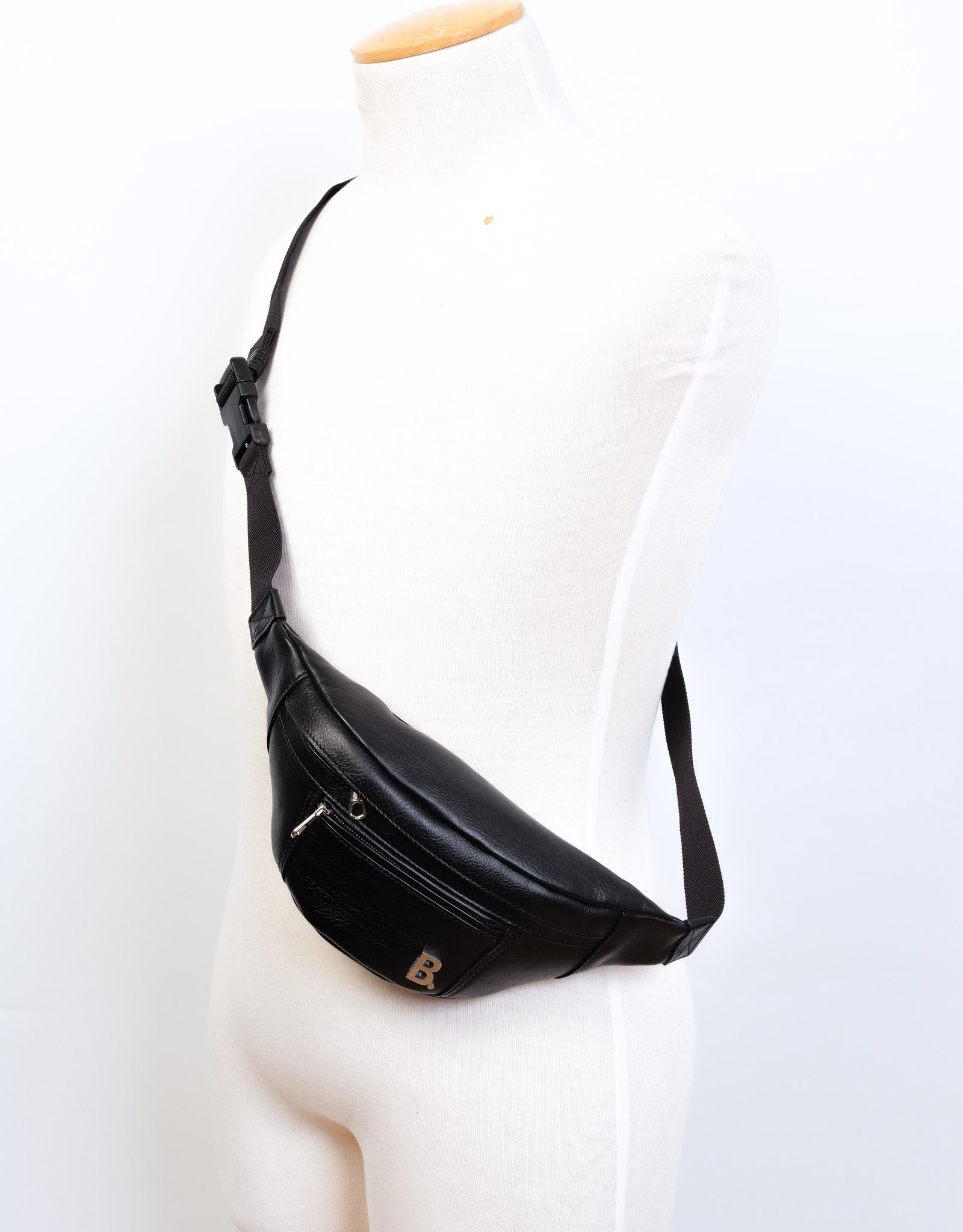 Ce sac ceinture est en cuir noir et présente une fermeture zippée sur le dessus, une poche zippée sur le devant, une plaque logo en métal sur le devant et des accessoires de couleur argentée.

COULEUR : Noir
CODE DE L'ÉLÉMENT : 530028 1000 W