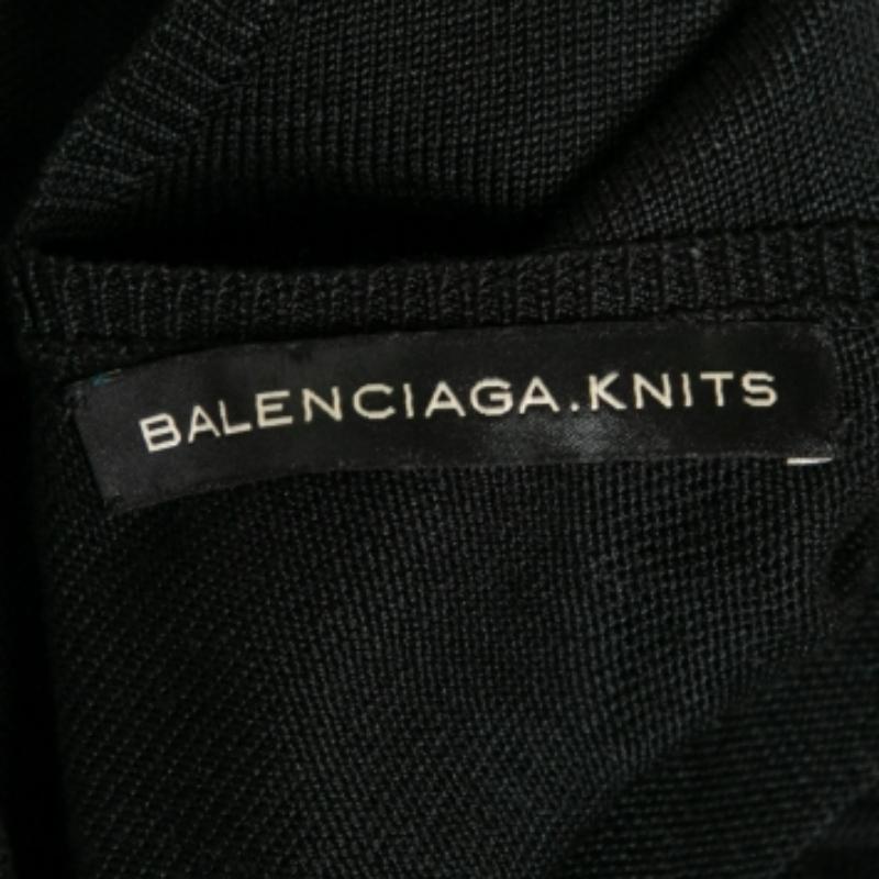 With this dress from the House of Balenciaga, comfort and elegance come easy! It is fashioned in black silk knit fabric and flaunts a low-cut backline, long sleeves, and embellishments on the shoulder. Match this Balenciaga dress with matching heels