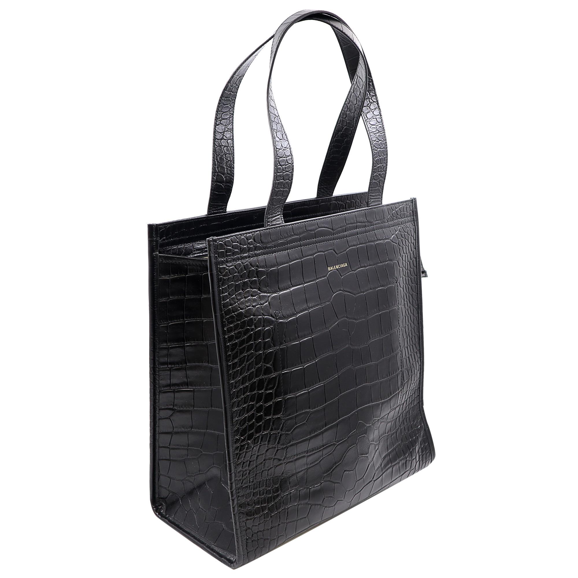 Balenciaga Bazar croc embossed leather tote bag. A timeless black hue and top handles, all very cleverly assembled to look the part of the Bazar bags you see in the market. A zipper secures the spacious interior of the bag with two interior slip