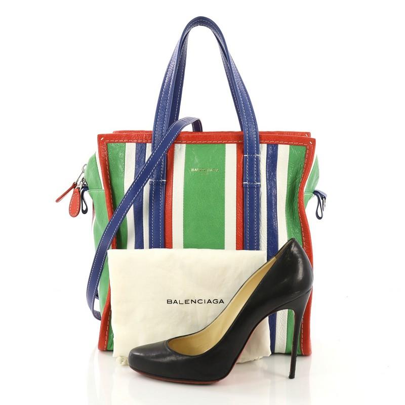 This Balenciaga Bazar Convertible Tote Striped Leather Small, crafted in green and white striped leather, features dual flat leather handles, contrast stitching, and silver-tone hardware. Its zip closure opens to a black fabric interior with zip and