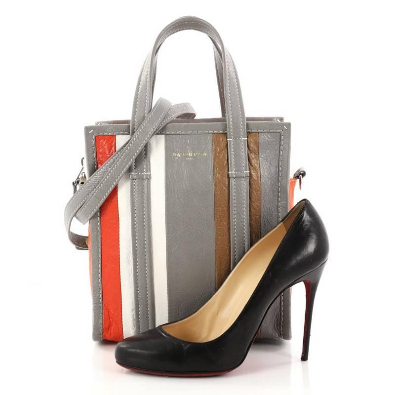 This authentic Balenciaga Bazar Convertible Tote Striped Leather XS is a stylish chic bag that's inspired by shoppers used in markets. Crafted in multicolor gray, white, brown, and orange striped leather, this bag features dual top leather handles,