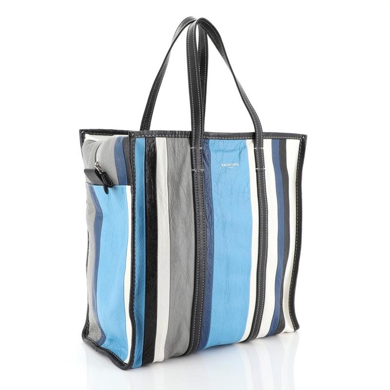 This Balenciaga Bazar Tote Striped Leather Medium, crafted in blue multicolor leather, features dual flat leather handles, contrast stitching, and silver-tone hardware. Its zip closure opens to a black fabric interior with zip and slip pockets.