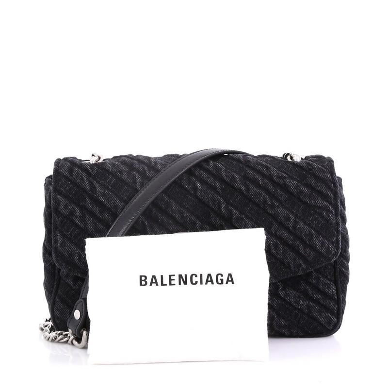 This Balenciaga BB Chain Round Shoulder Bag Quilted Denim Small, crafted from black quilted denim, features a chain link strap with leather shoulder pad, BB logo on the flap, and aged silver-tone hardware. Its magnetic snap closure opens to a black