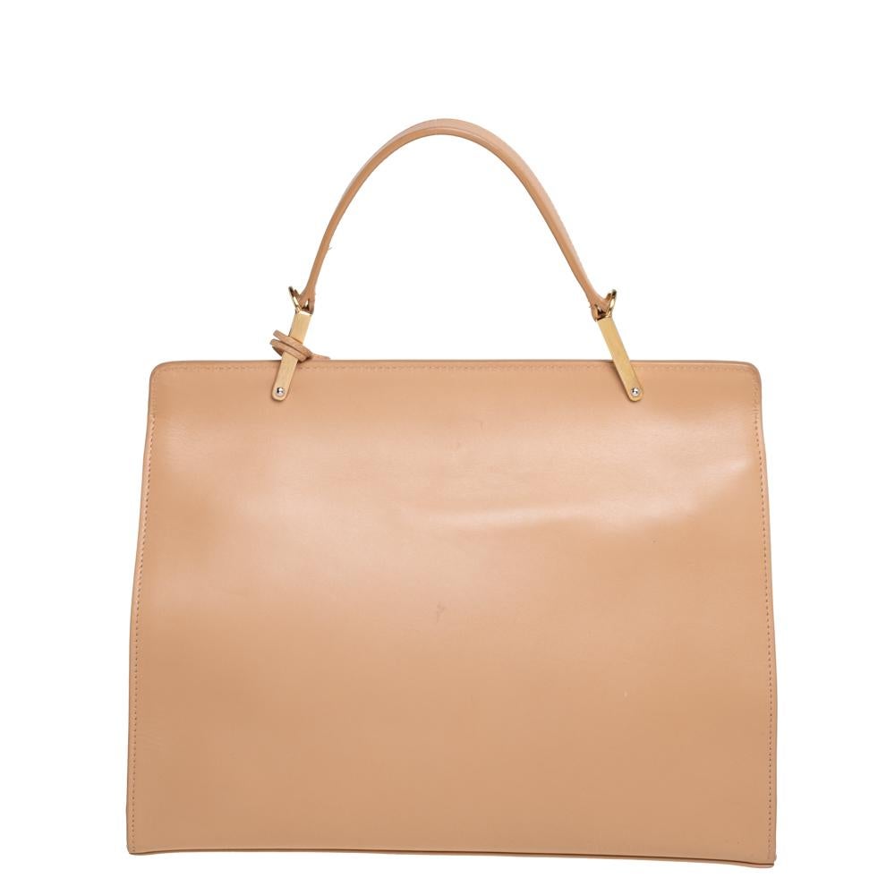 Balenciaga's Le Dix Cartable bag features a sleek and sophisticated silhouette enhanced by a beige hue. Skillfully made from high-quality leather, it comes with a front flap that opens to an interior spacious enough for work essentials. Carry it by