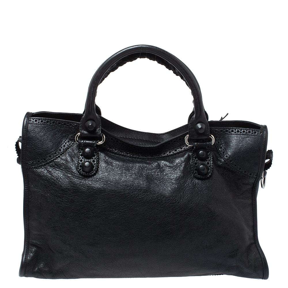 This dressy Balenciaga City tote made from leather is unique in its silhouette and features an interplay of large studs and buckles. With a lovely shade, the GH City tote has a front zip pocket, and leather handles. The zip-top closure opens to a