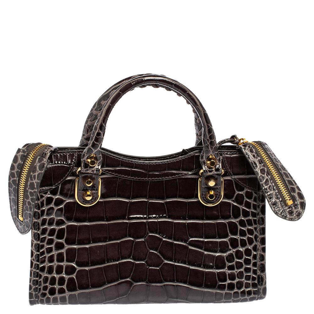 Crafted with a croc-embossed leather exterior and gold-tone metal detailing, this bag from Balenciaga is gorgeous in appearance and construction. It has optimal storage space for your personal belongings and comes with two handles and an adjustable