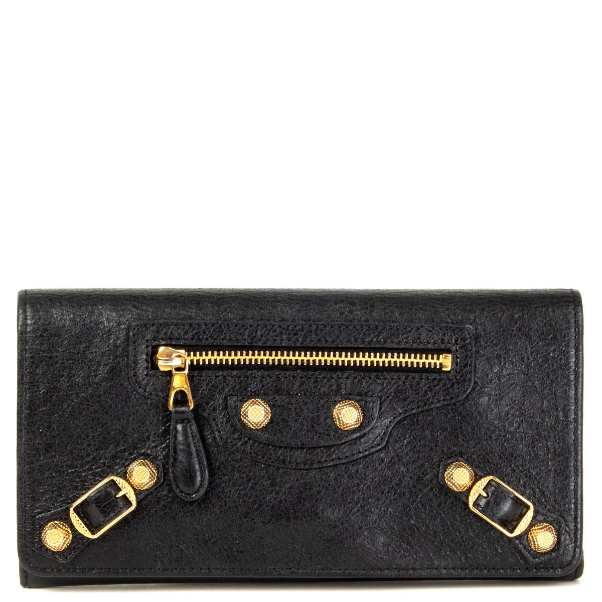 100% authentic Balenciaga 'Giant Money' continental wallet in black distressed leather featuring gold-tone hardware. Opens with a magnetic button under the flap. Lined in black leather and nylon. Divided in three compartments with one big zipped