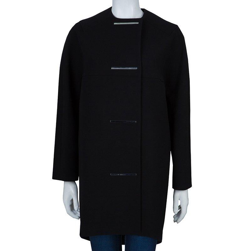 Balenciaga cocoon coat is emblematic of feminine grace in the minimalistic design. Crafted from a polyester based fabric, the lining is a blend of acetate and silk. The black coat is single breasted, with silver tone metal stitched in place of