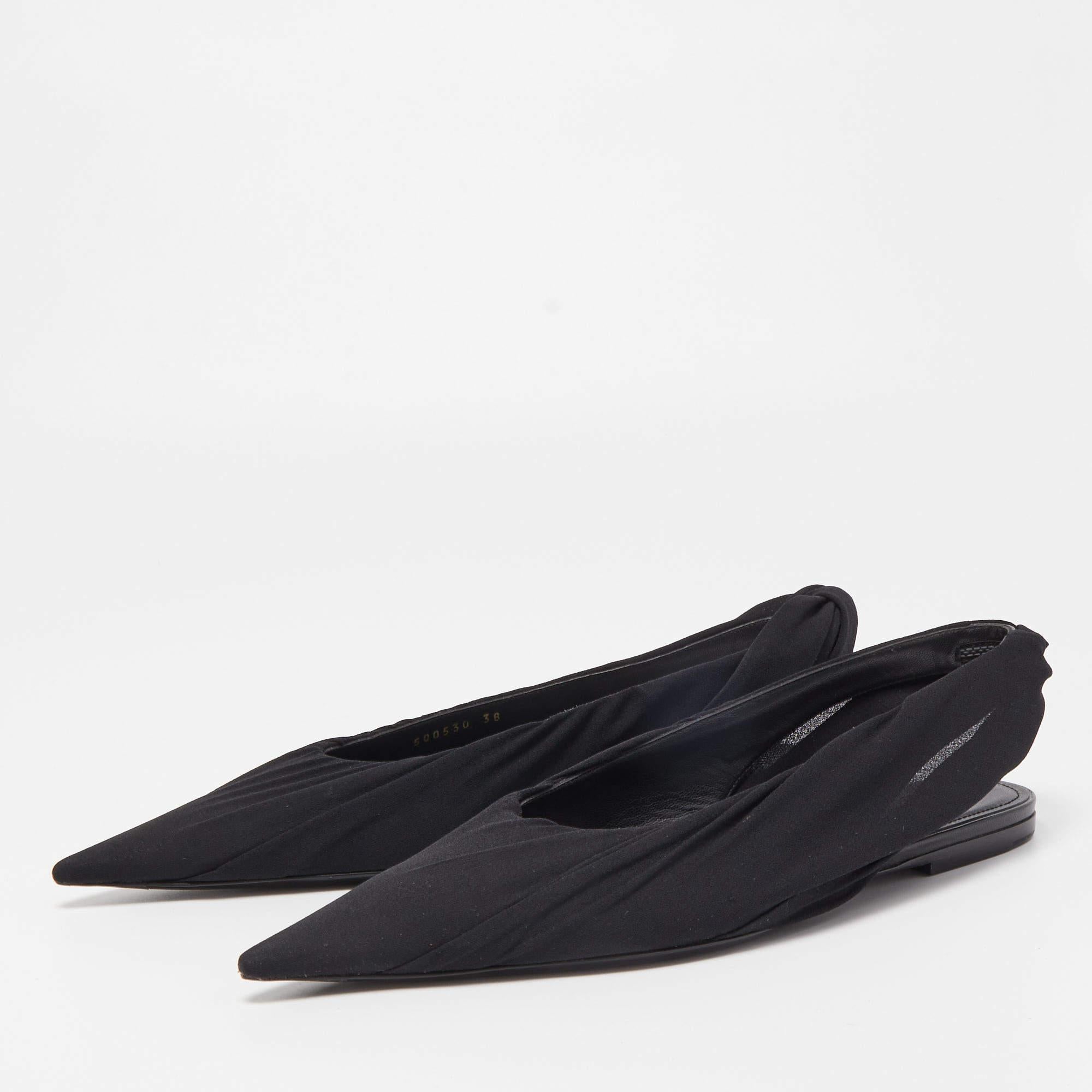 The Balenciaga flats are elegant and versatile footwear. Crafted from sleek black fabric, they feature a pointed toe and a slender slingback strap for a chic, minimalist look. These flats offer comfort and style, making them a perfect choice for