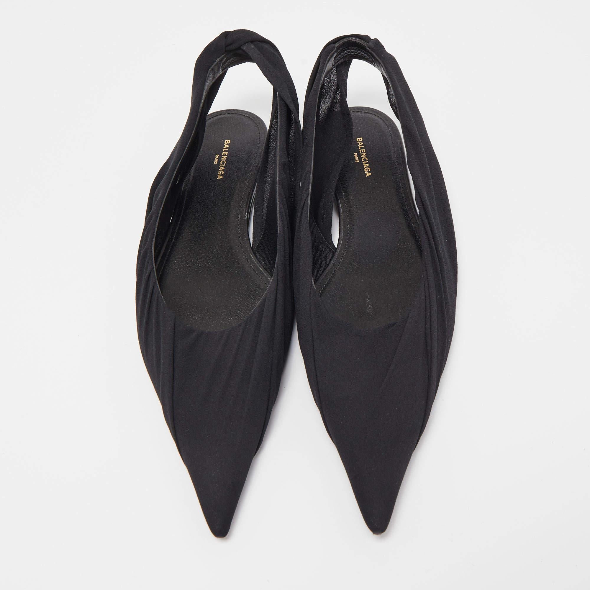 The Balenciaga flats are elegant and versatile footwear. Crafted from sleek black fabric, they feature a pointed toe and a slender slingback strap for a chic, minimalist look. These flats offer comfort and style, making them a perfect choice for