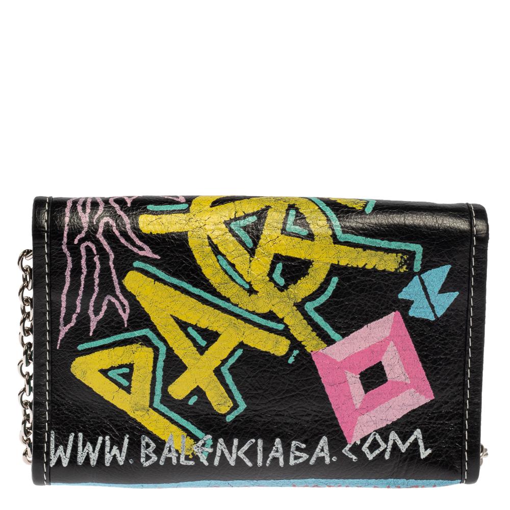 Balenciaga gives the touch to our everyday partner, the shoulder bag, via this pretty creation. Made from leather, the bag has a colorful graffiti print all over and a chainlink shoulder strap. A flap secures the spacious interior of the bag for