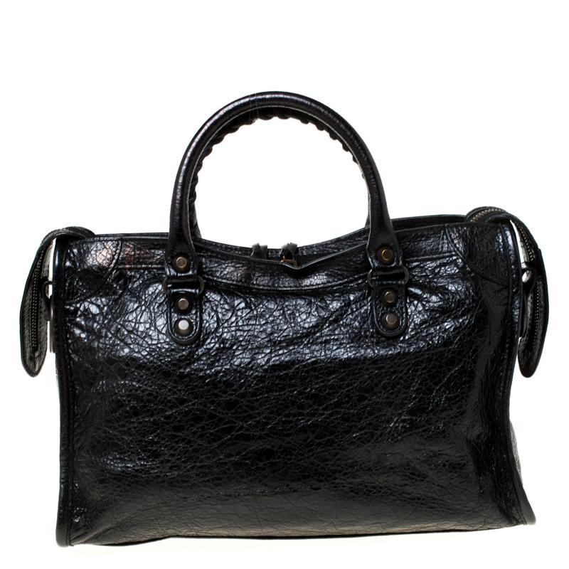 This Balenciaga City tote is a classic! Crafted from leather in a gorgeous black hue, the bag has a feminine silhouette with two top handles, a removable shoulder strap, and gold-tone hardware. The zipper closure opens to a fabric-lined interior and