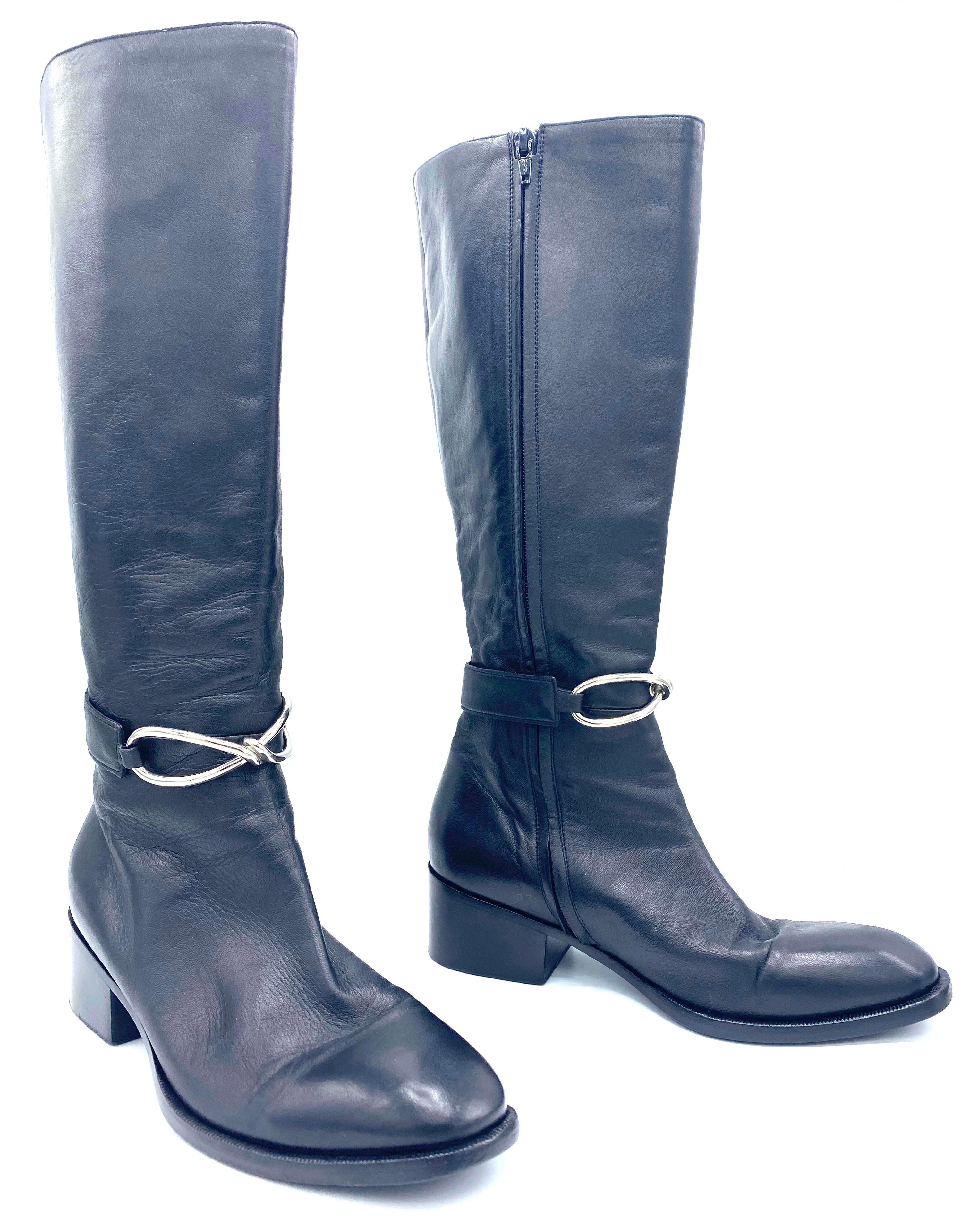 Product details:

The boots are made out of black leather, they feature silver tone hardware at the front, inside concealed closure, knee height fit and the heel height is 2 inches.