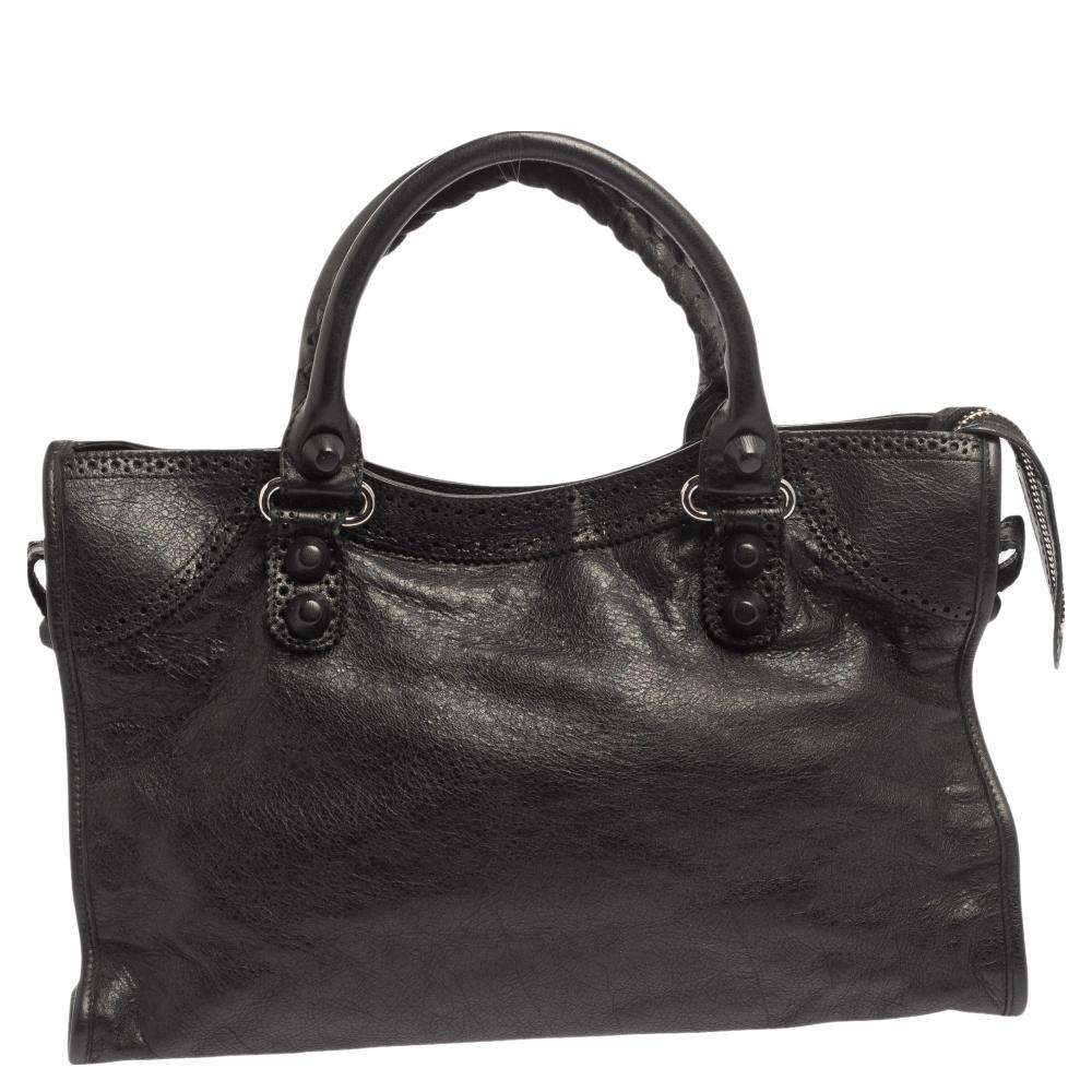 This Balenciaga City bag is perfect for everyday use. Crafted from leather in a gorgeous black hue, the bag has a feminine silhouette with two top handles and silver-tone hardware. The zipper closure opens to a fabric-lined interior and the bag is