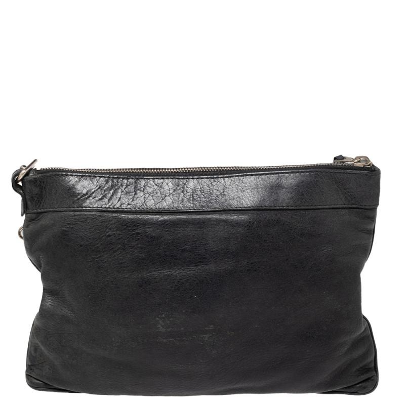 This Balenciaga clutch is a stylish creation that is exceptionally well-made. It is crafted from leather and accented with signature metal studs, corner buckle detailing, and a front zip pocket. The interior is lined with fabric and allows easy