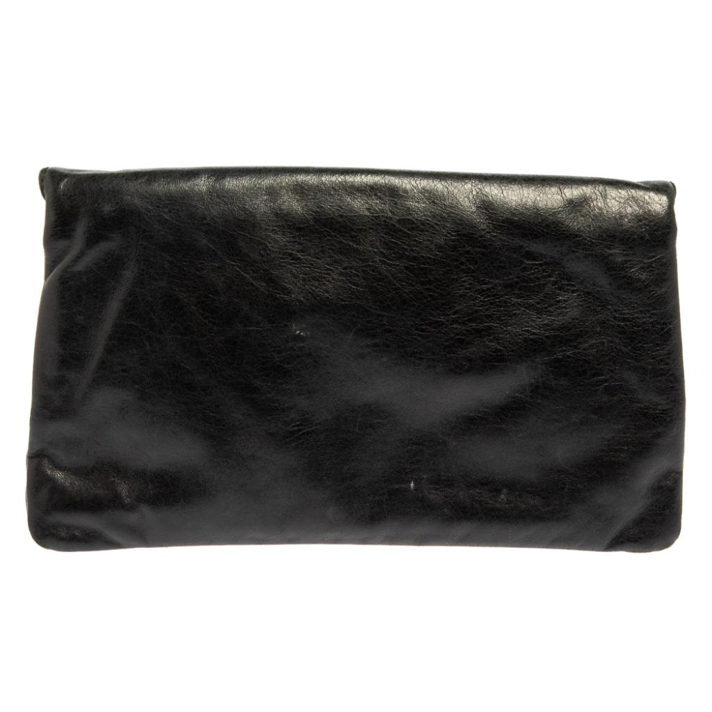 This Balenciaga clutch is a stylish creation that is exceptionally well-made. This flap-style clutch is crafted from leather and accented with signature metal studs, corner buckle detailing, and a front zip pocket. The interior is lined with fabric