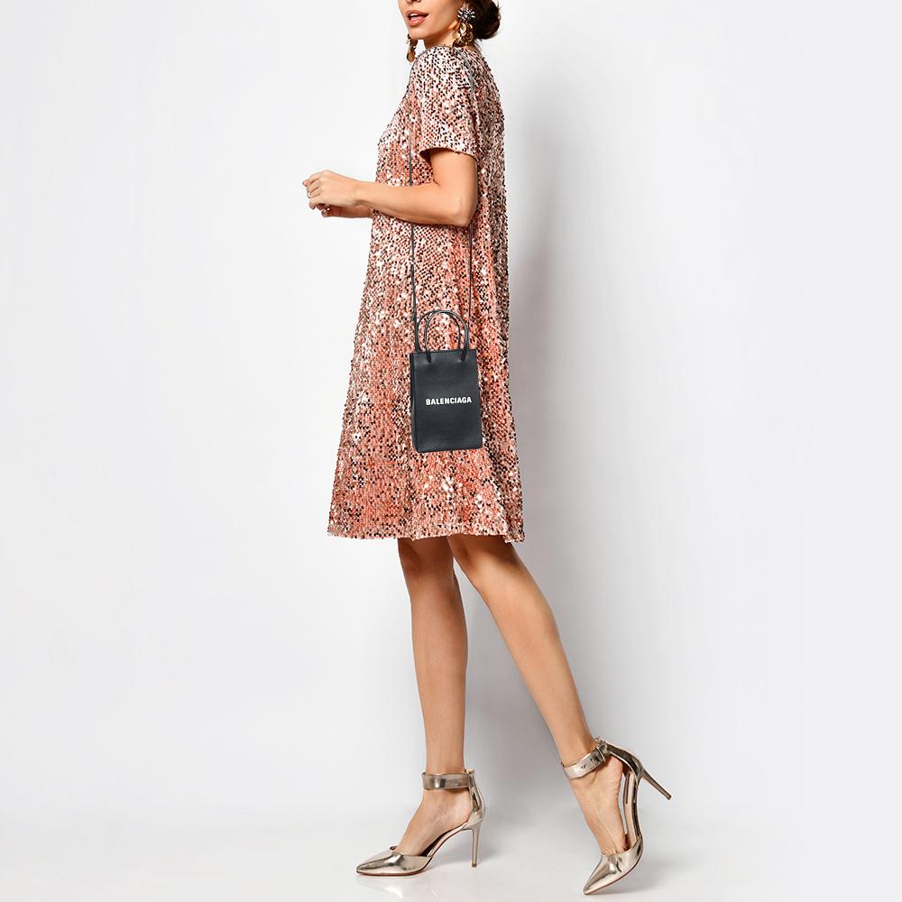 The Balenciaga crossbody bag is a luxurious accessory. Crafted from high-quality black leather, it features a sleek, compact design with a phone pocket, card slots, and a detachable crossbody strap for hands-free convenience. It exudes modern
