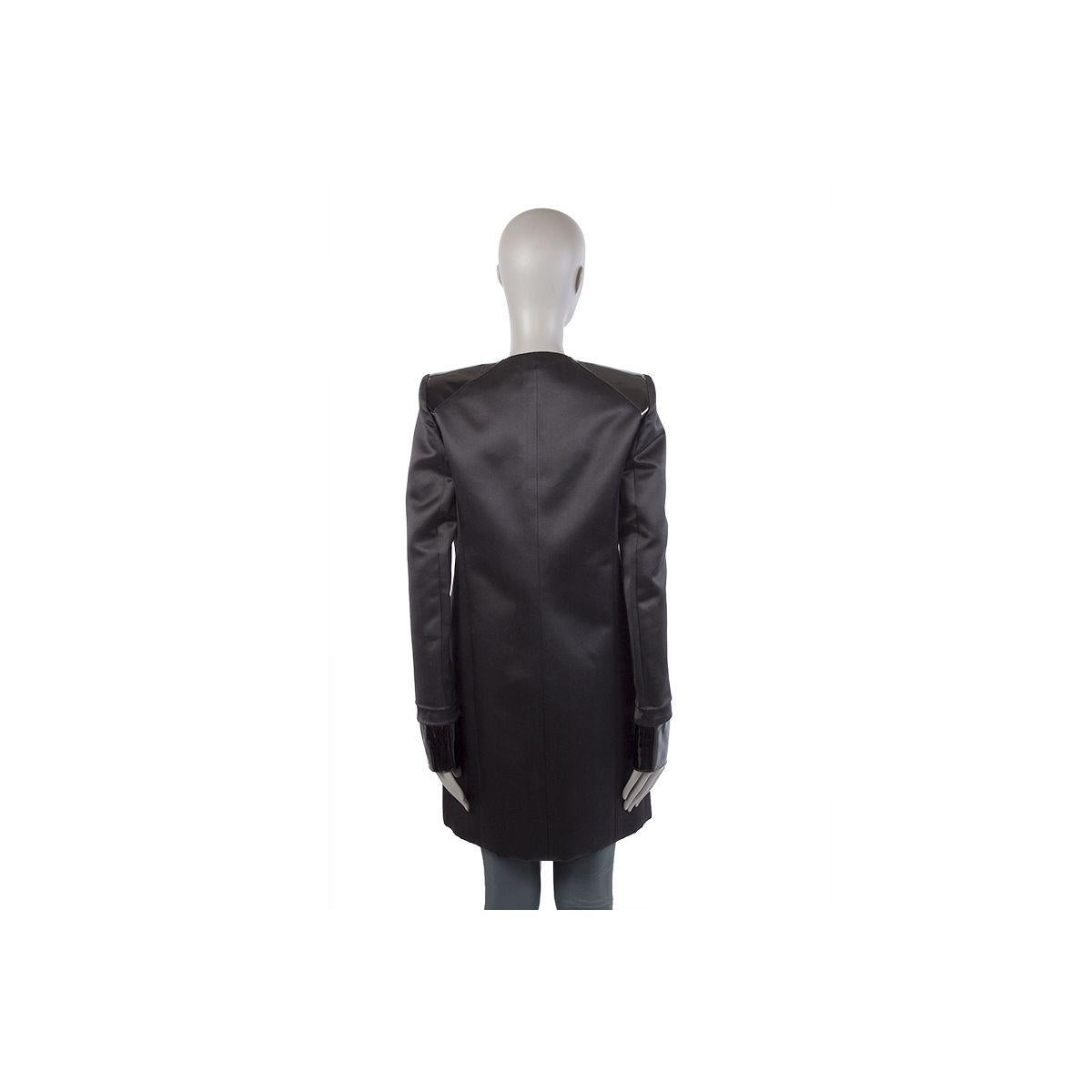 100% authentic Balenciaga long collarless open coat in black silk (100%). With two welt chest pockets, two slit pockets on the front and shoulder detail, cuffs and pocket inserts in black lambskin patent. Lined in black and off-white (silk (100%).
