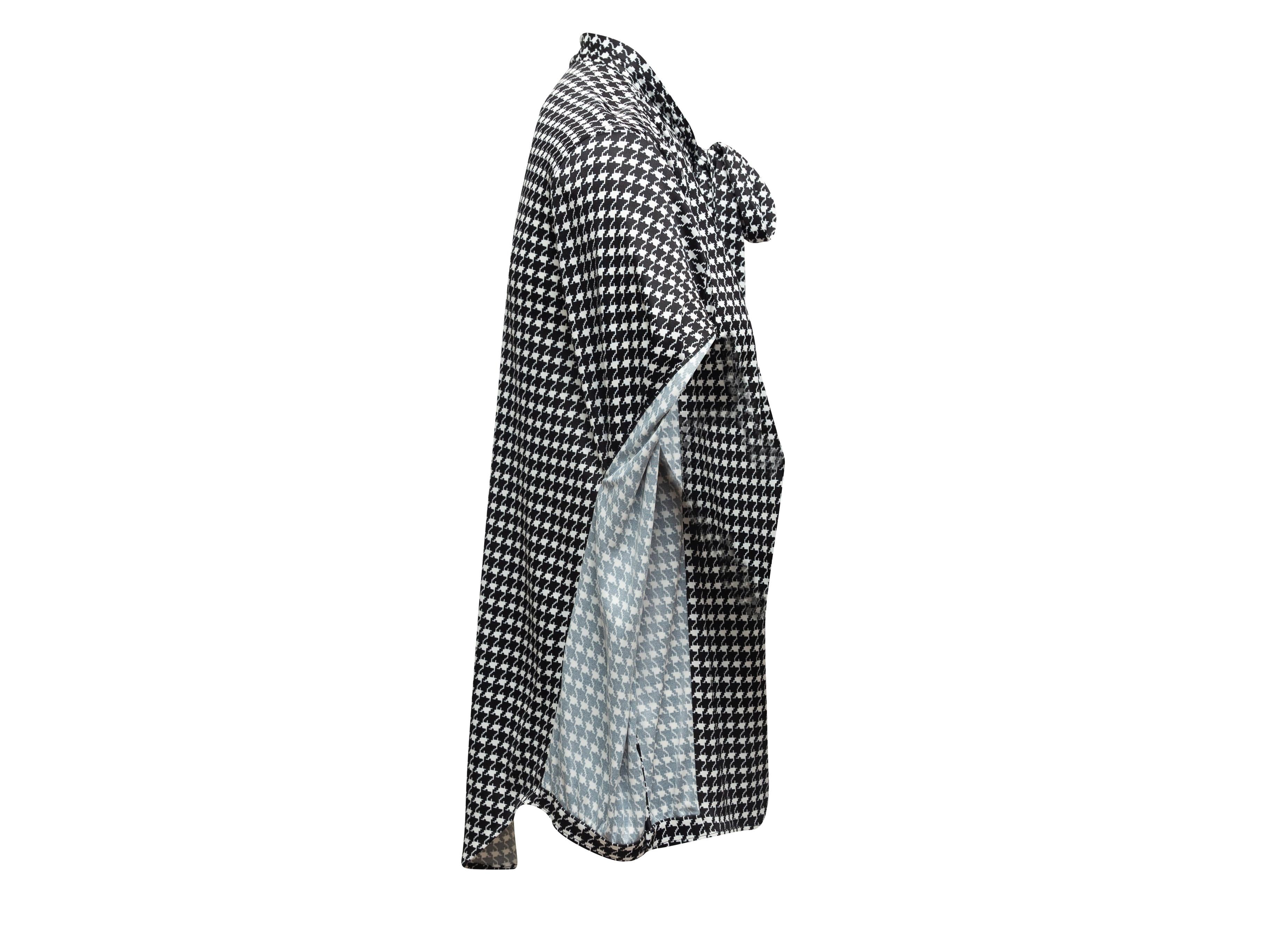 Product details: Black and white long sleeve blouse by Balenciaga. Houndstooth print throughout. Pussy bow tie at neck. Button closures at center front. Designer size 36. 32