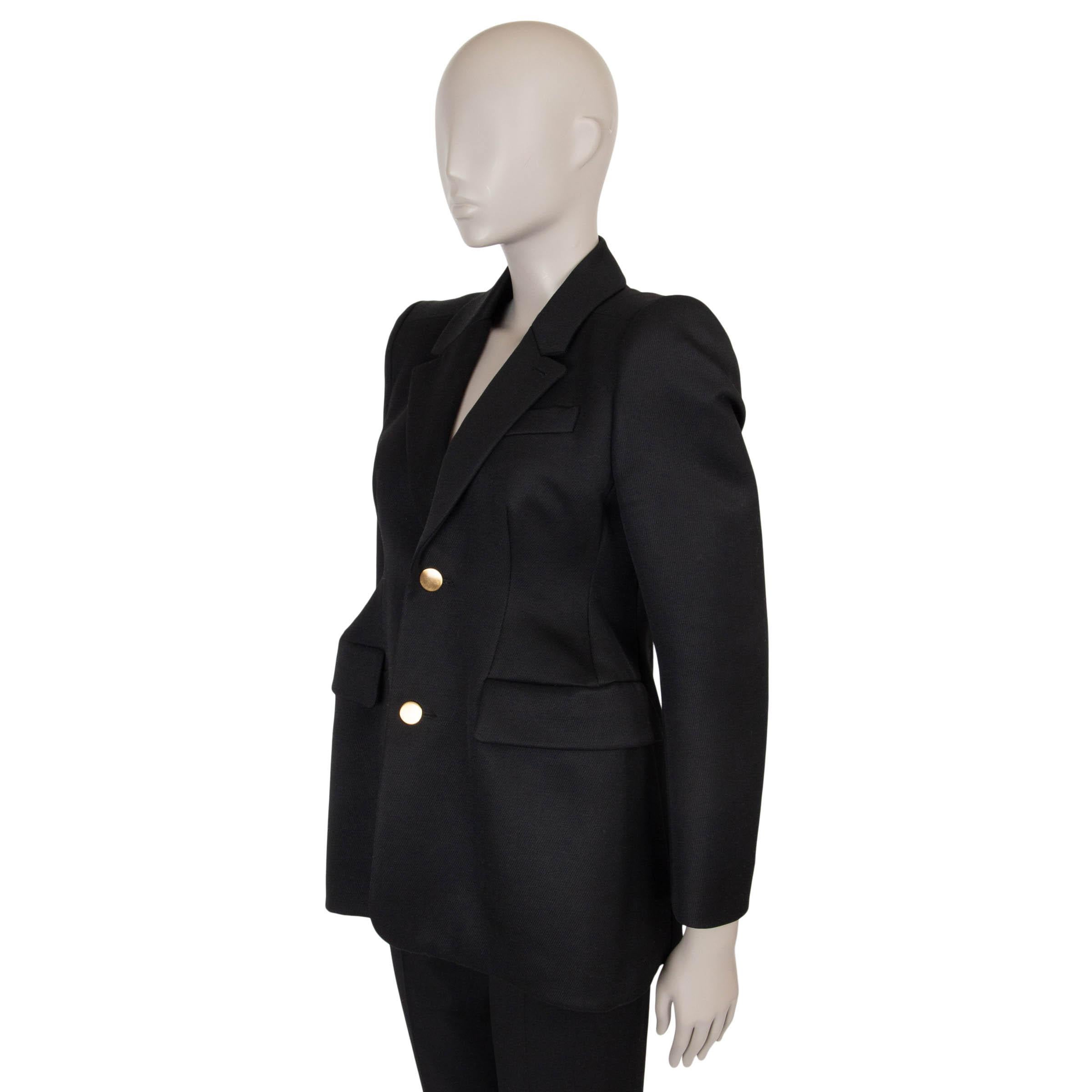 Questo blazer aderente e strutturato di Balenciaga, autentico al 100%, è realizzato in lana nera al 100% e presenta fianchi accentuati e spalle pad per una silhouette d'effetto. Con un colletto classico, tasche laterali a fessura e due bottoni