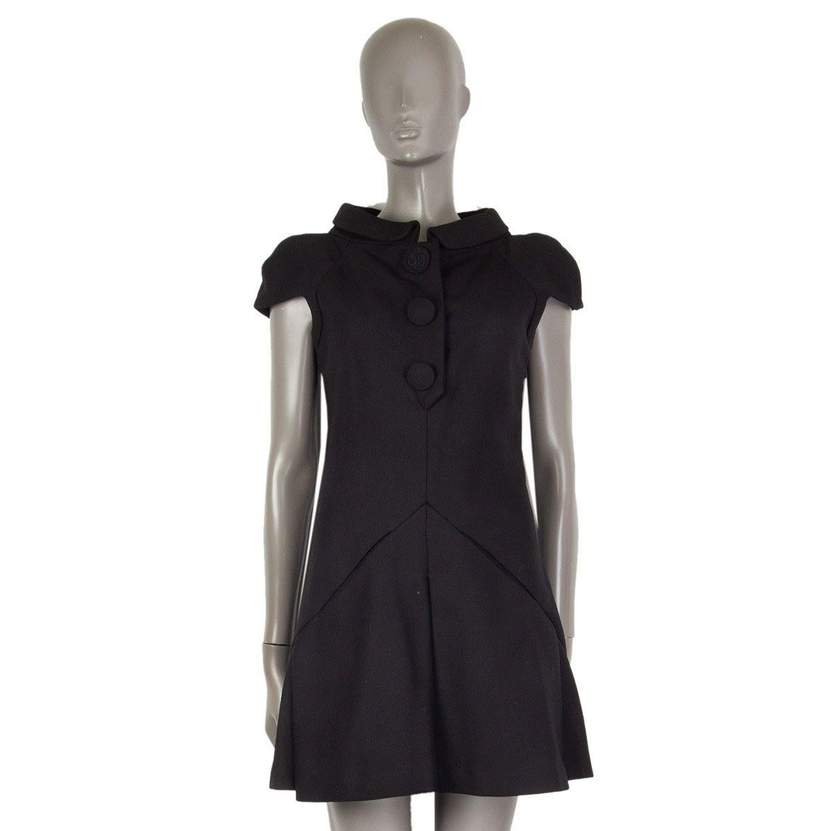 authentic Balenciaga short sleeves button-logo embellished dress in black wool (100%) with a flared and pleated skirt and with a basque cut and two slit pockets in it. Closes with a zipper on the side and concealed buttons on the front. Lined in