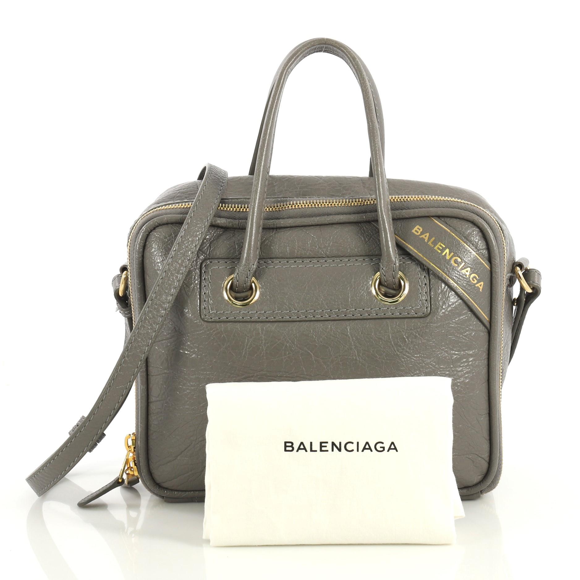 This Balenciaga Blanket Square Bag Leather Small, crafted from gray leather, features dual rolled leather handles, logo flag at left corner and gold-tone hardware. Its all-around zip closure opens to a black fabric and gray leather interior with two