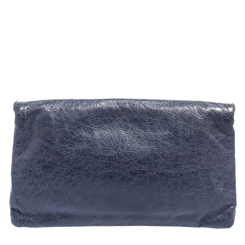 This pretty Balenciaga clutch is a stylish creation that is exceptionally well-made. This flap-style clutch is crafted from leather and accented with signature silver-tone studs, corner buckle detailing, and a front zip pocket. The interior is lined