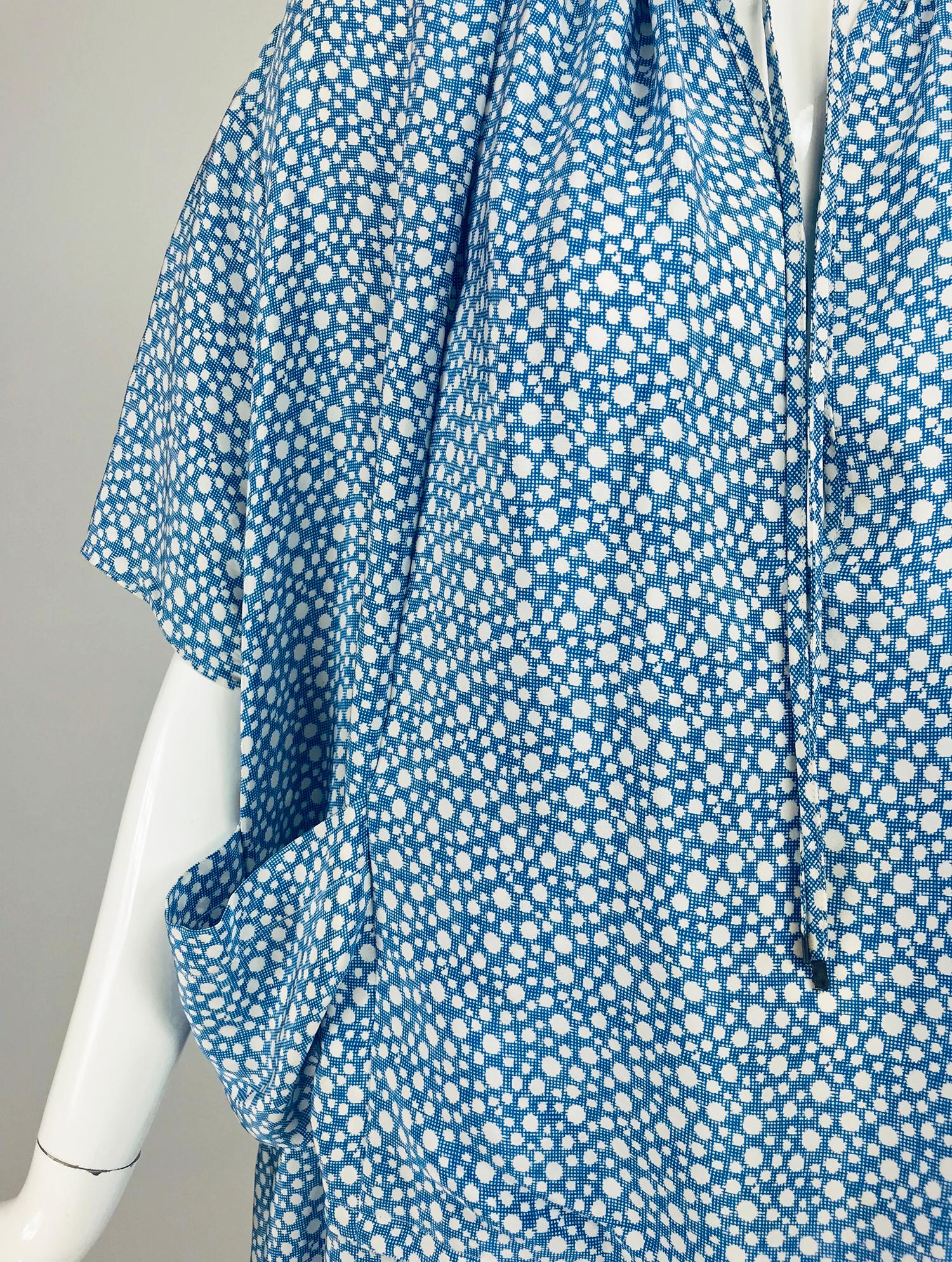 Balenciaga blue and white silk dot and small square print asymmetrical dress. Smock style dress is gathered at the round neckline and closes with a tie at the front. 
 Yoke shoulder with full short sleeves, the sleeves can be gathered via a band