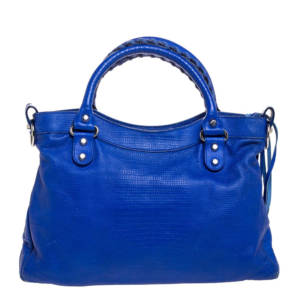 This Balenciaga Town tote will never leave you unnoticed. The lovely blue lizard-embossed leather exterior is detailed with silver-tone studs and buckle motifs, a front zip pocket, and double handles. It also has a detachable and adjustable shoulder